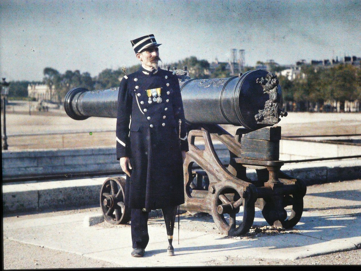 Um soldado de uniforme com três medalhas está de pé ao lado de um canhão em Paris, 1918 (autocrômico) de Jules Gervais Courtellemont