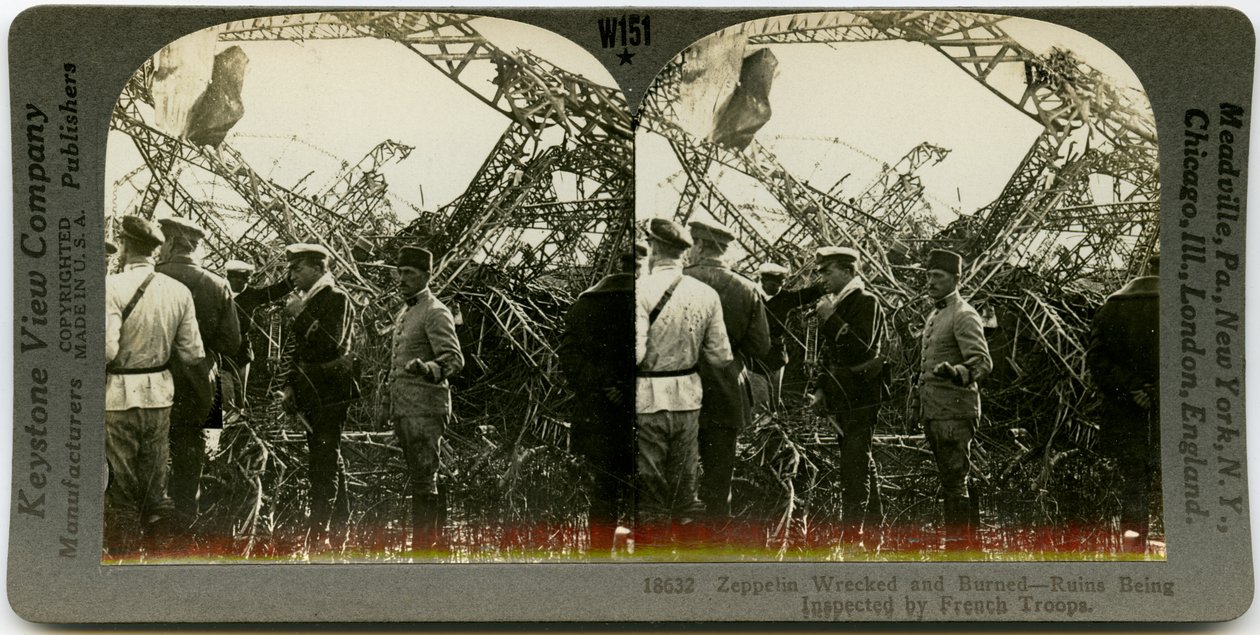 Estéreo horizontal, sépia, mostrando um grupo de homens uniformizados inspecionando os destroços de um zepelim. Keystone Stereograph number 18632. O título diz de Keystone View Company