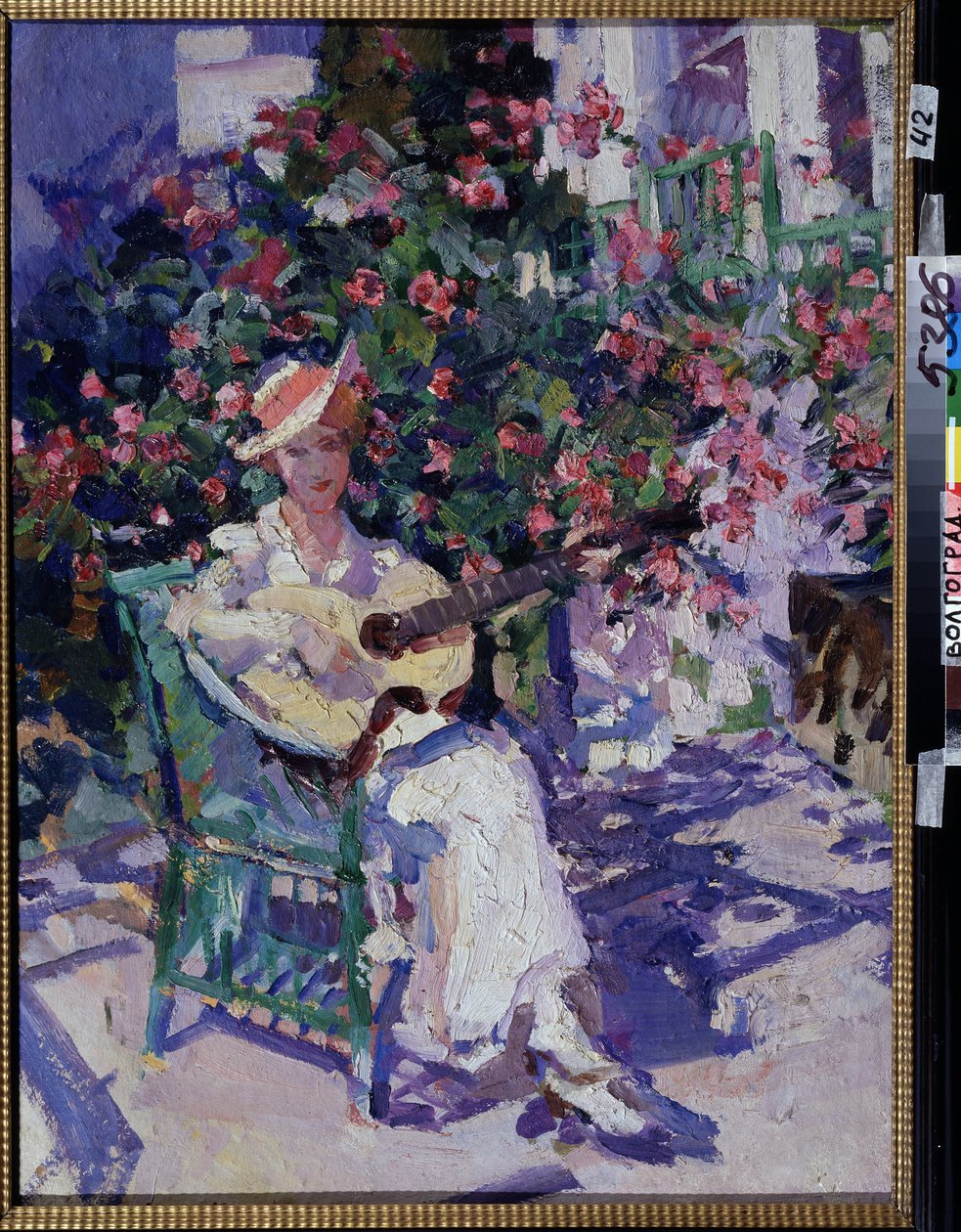 Na Crimeia (Na Crimeia). Uma jovem de vestido leve e leve, sentada em uma cadeira de jardim, em frente a um bosque florido, toca violão, em pleno verão, na região litorânea do Golfo da Crimeia. Pintura de Konstantin Alexeyevich Korovin (Constan de Konstantin Alekseevich Korovin