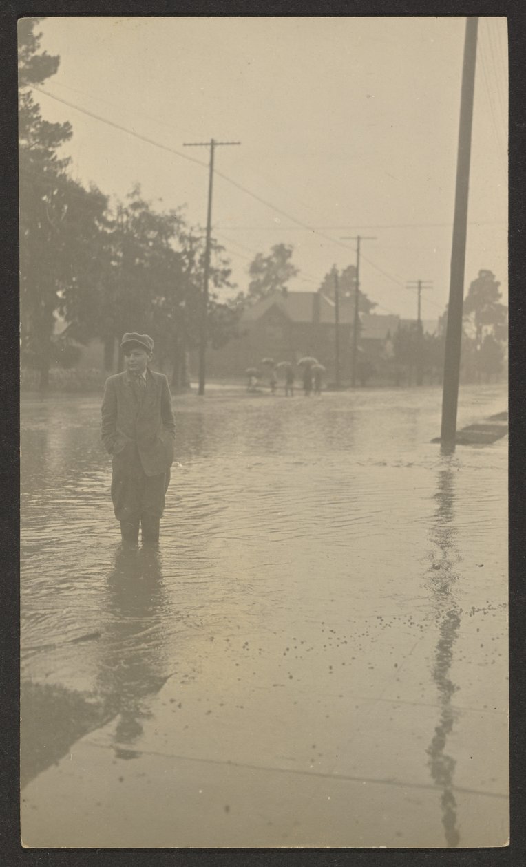 [Rapaz em pé numa rua inundada]. de Louis Fleckenstein