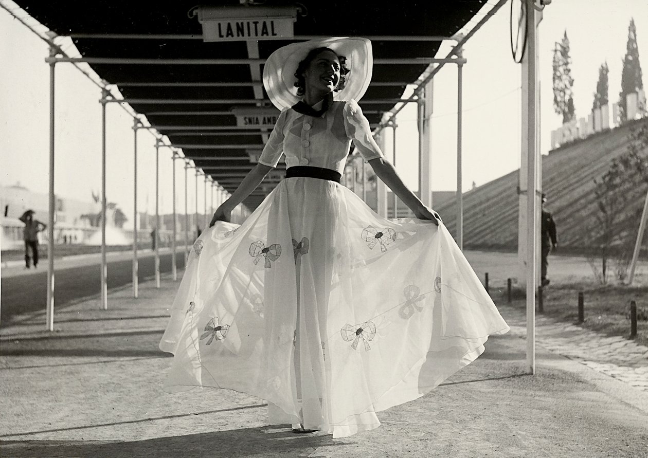 Modelo com um vestido de verão completo criado pela casa de alta costura "Graldi". O vestido é de tecido leve decorado com bordado; um chapéu de aba larga completa o conjunto. (foto a p/b) de Luis Bogino