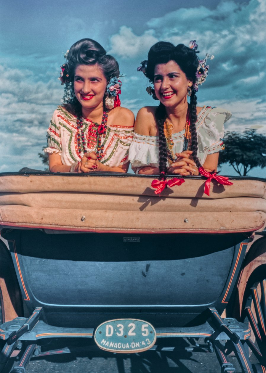 Jovens mulheres nicaraguenses posam em trajes festivos e chapéus na parte de trás de uma carruagem ak... de Luis Marden
