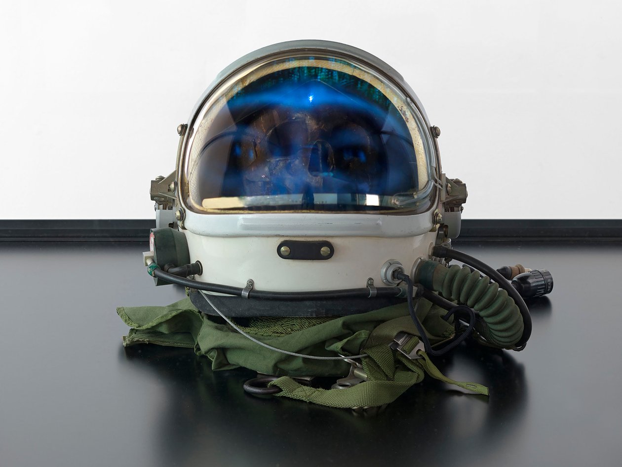 Alpha Omega, 2016 (Vidro, ecrã LCD, leitor multimédia, réplica de crânio, capacete espacial, madeira) de Mat Collishaw