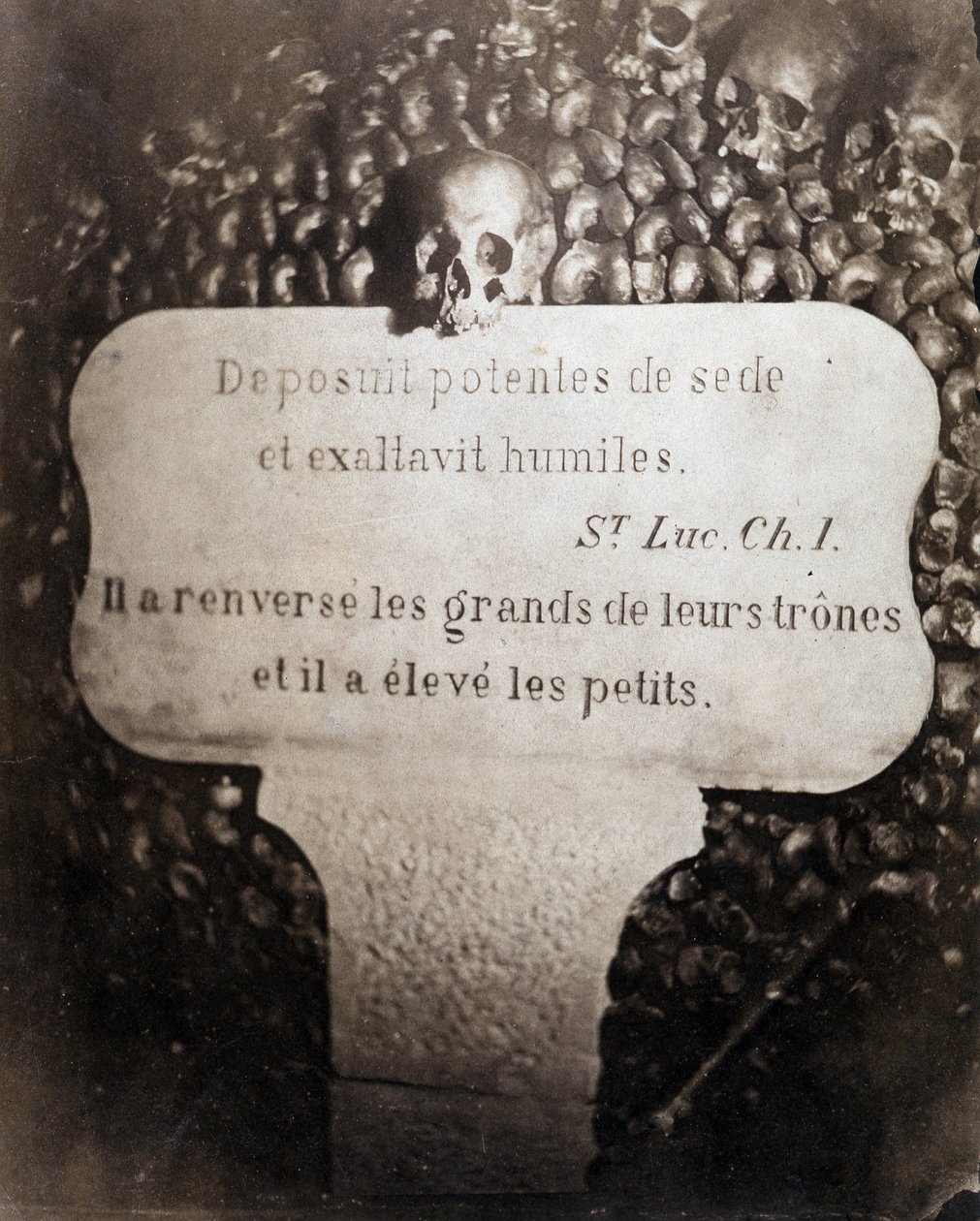 Os ossuários das catacumbas de Paris. Pedro com uma citação do capítulo 1 do Evangelho de São Lucas (Deposuit potentes de sede et exaltavit humiles. Em francês: Ele derrubou os grandes e levantou os pequenos) de Nadar