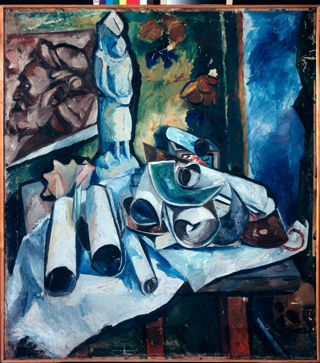 Natureza morta com os rolos de papel (desordem num atelier de artistas, com uma estatueta, uma pintura do rosto de um homem e um crânio) - Natureza morta (Natureza morta com os rolos de papel) - Pintura de Olga Vladimirovna Rozanova (1886-1918), óleo sobre de Olga Wladimirowna  Rosanowa