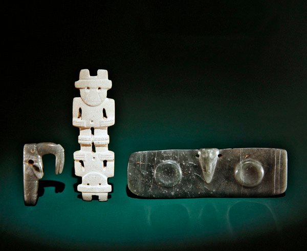 Figuras esculpidas, incluindo uma ave de bico, uma estatueta de duas cabeças e um pingente alado, de Guacimo, área de Linea Vieja (jade) de Pre Columbian Pre Columbian