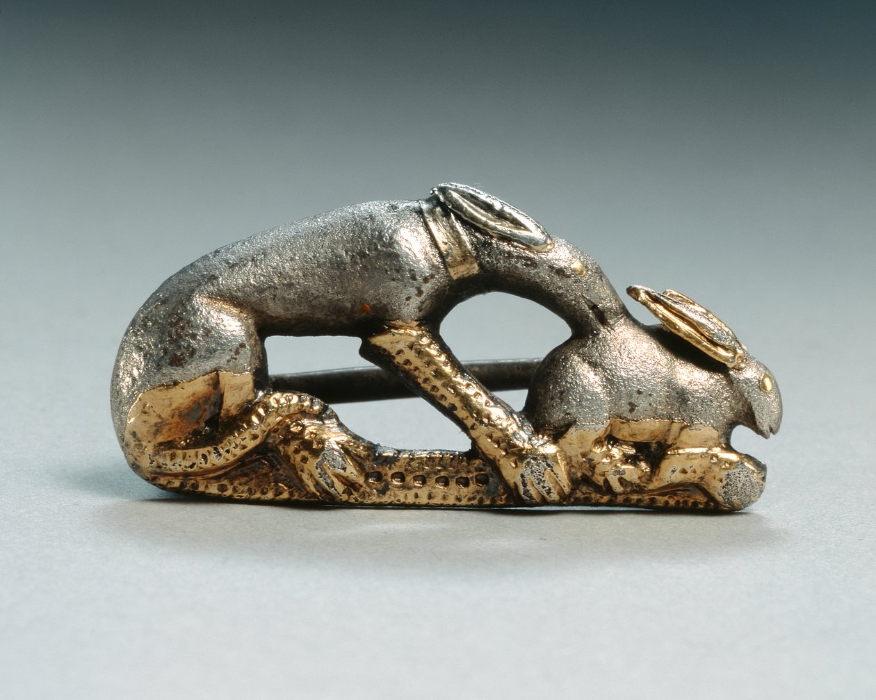 Fíbula de um cão a apanhar um coelho (prateado e dourado) de Roman