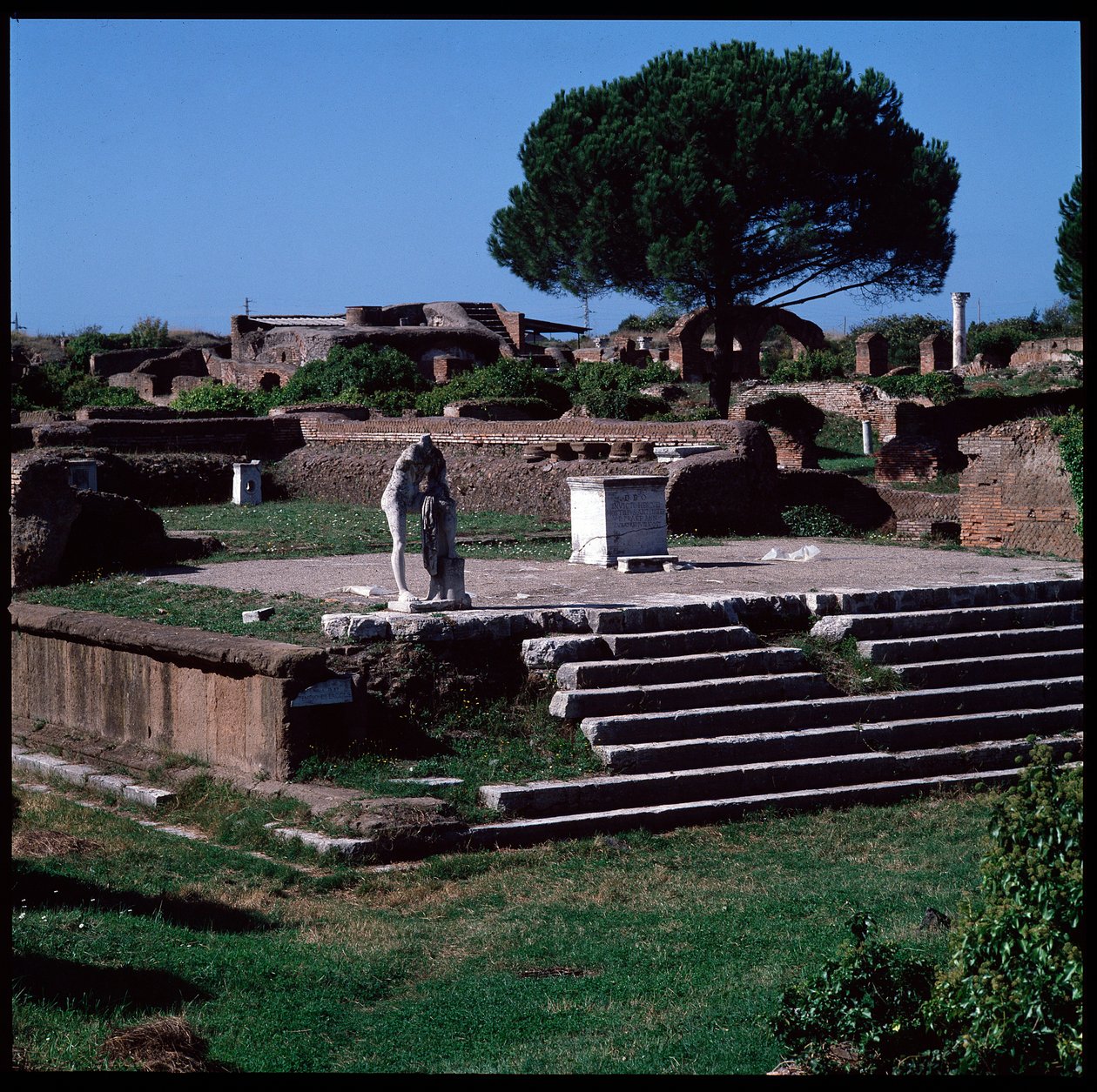 Arte romana: vista das ruínas do templo de Hércules e estátua de Gaio Cartilius Popplicola, cidadão de Ostia de Roman