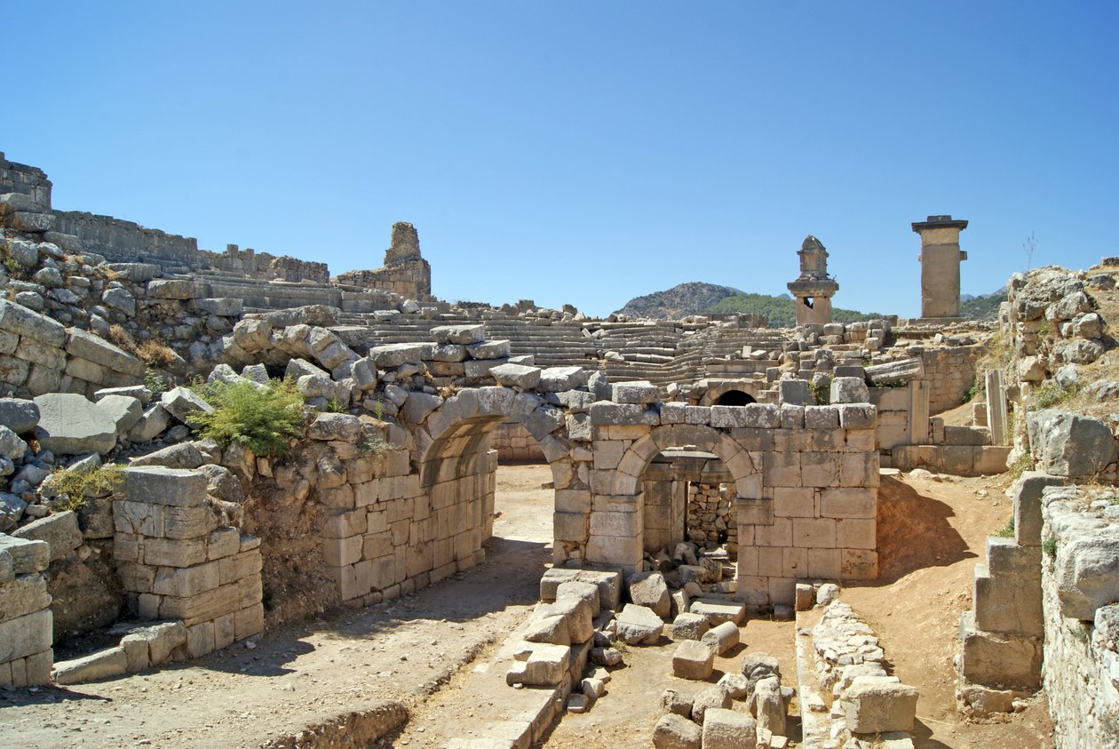 Vista através da entrada abobadada do teatro Xanthos no fosso da Orquestra, mostrando pilar e túmulo de Harpia, Xanthos, Turquia (foto) de Roman