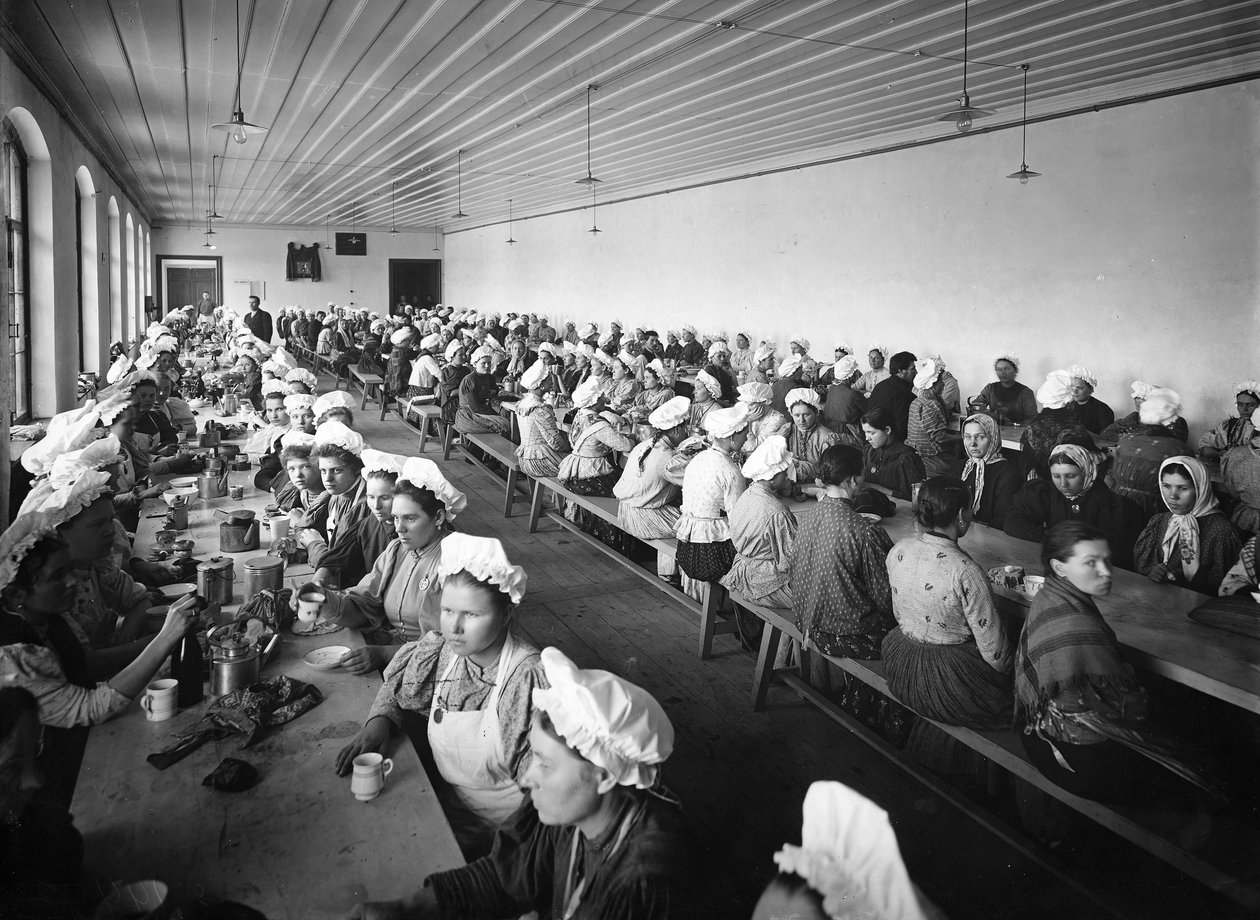 Mulheres trabalhadoras em um depósito de fábrica fazem um intervalo para o jantar, supervisionadas por alguns supervisores masculinos de Russian Photographer