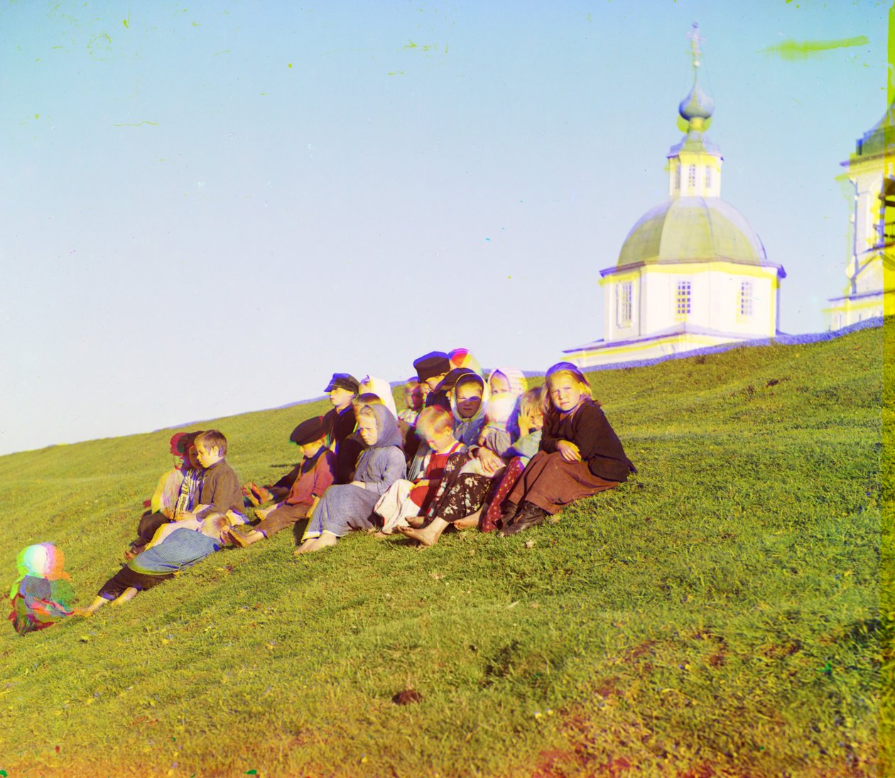 Crianças russas, sentando, ligado, a, lado, de, um, colina, perto, um, igreja, e, torre sino, em, a, campo, perto, branca, lago, em, a, norte, de, europeu, rússia, 1905-1915 de Sergey Prokudin Gorsky