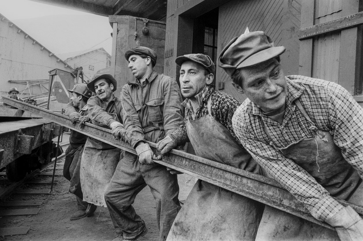 Trabalhadores da mina juntam-se para mover um pesado carril de aço na mina de cobre El Teniente... de Ted Spiegel