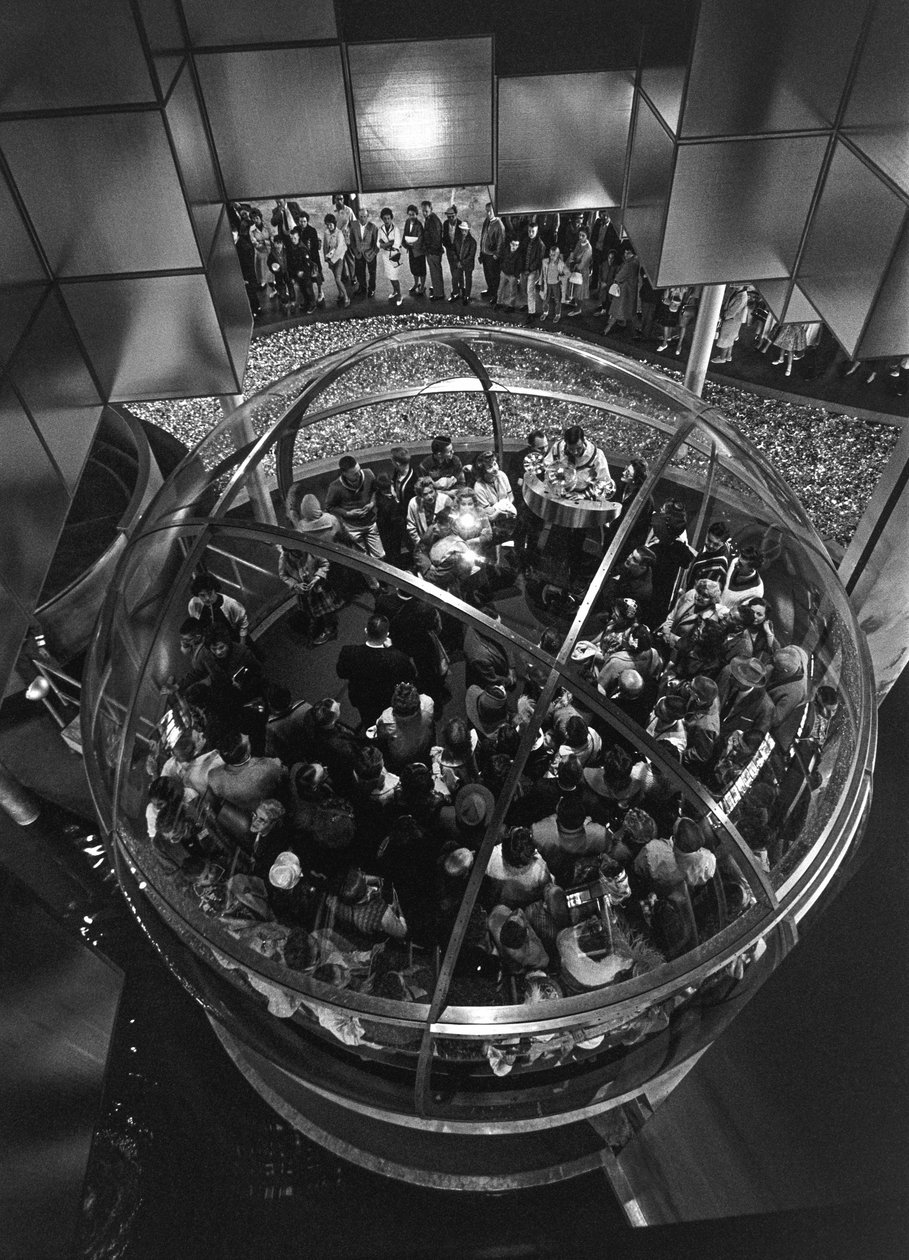 Visitantes da Feira Mundial de Seattle dentro de um elevador abobadado numa exposição de Ted Spiegel