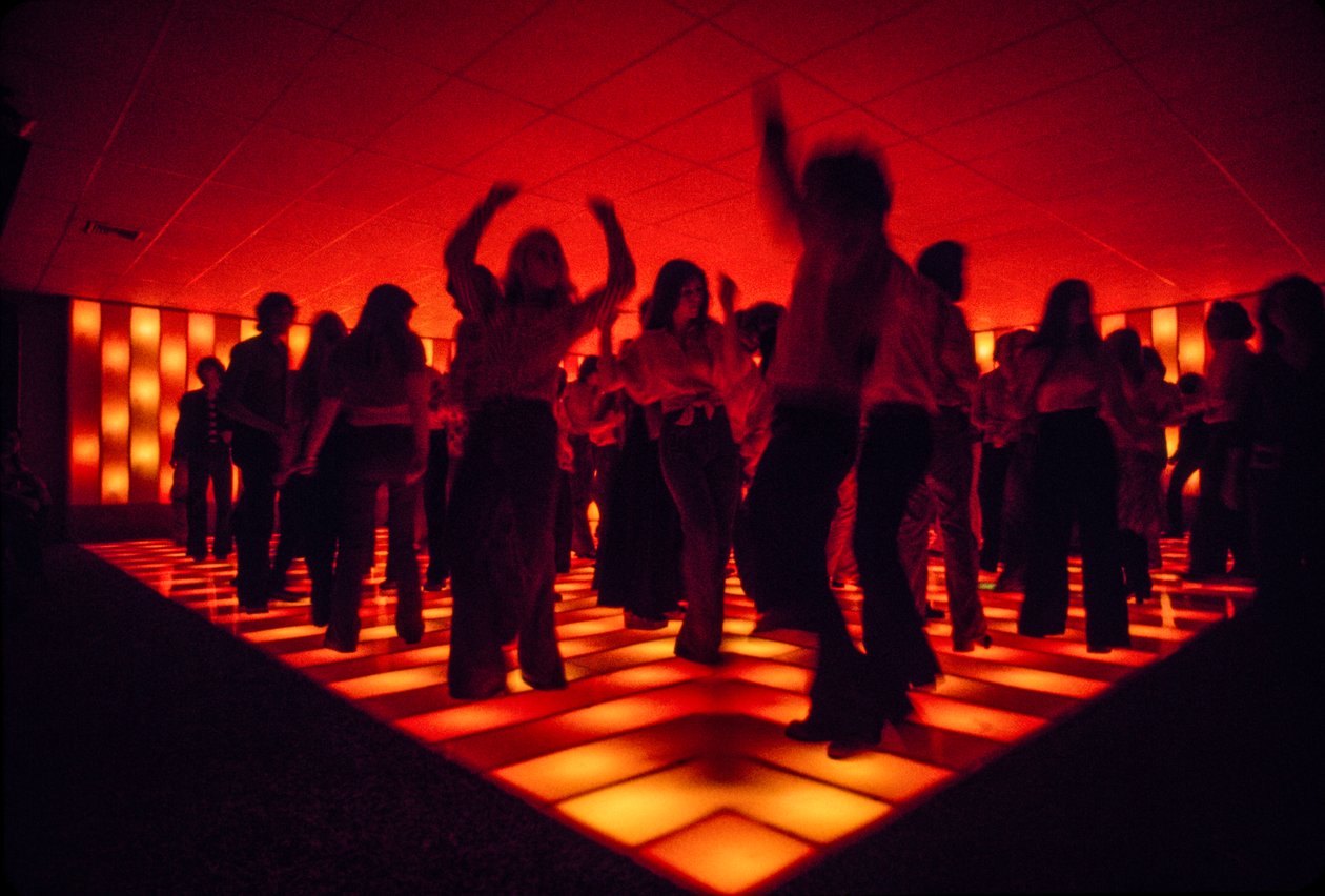 Jovens bailarinos numa discoteca a dançar numa pista iluminada de Ted Spiegel