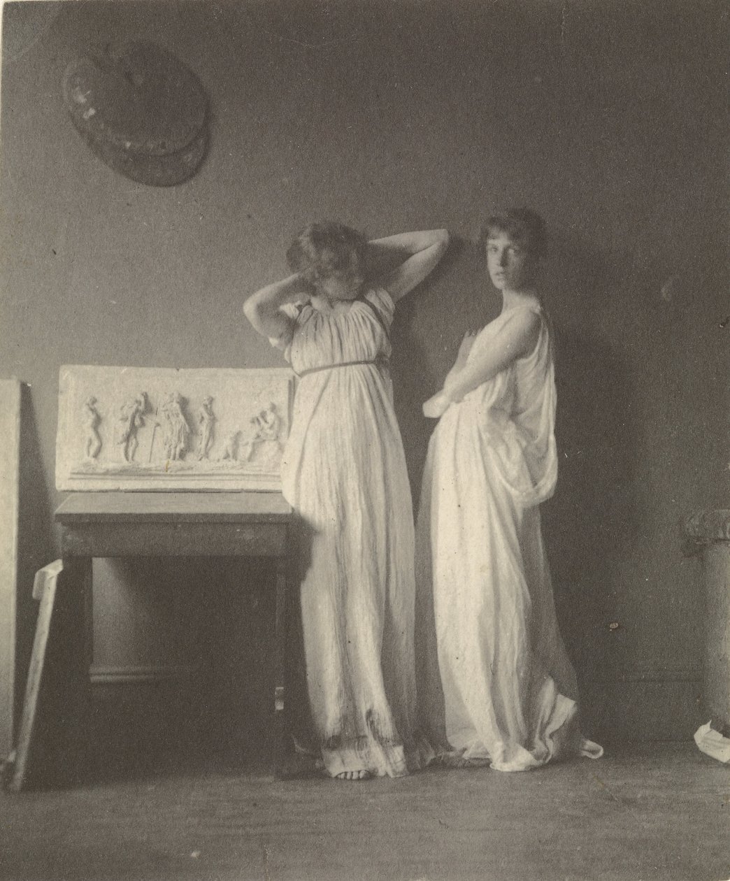 (Dois modelos femininos em traje clássico com Eakins Sculpture Arcadia). de Thomas Eakins