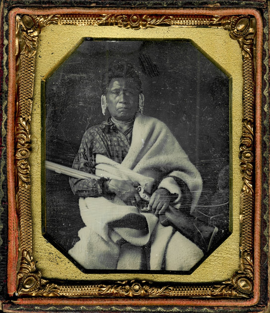 Retrato de Nacheninga [nenhum coração do medo], Iowa. Nacheninga segura uma arma nas mãos e está envolto num cobertor grosso. de Thomas M. Easterly