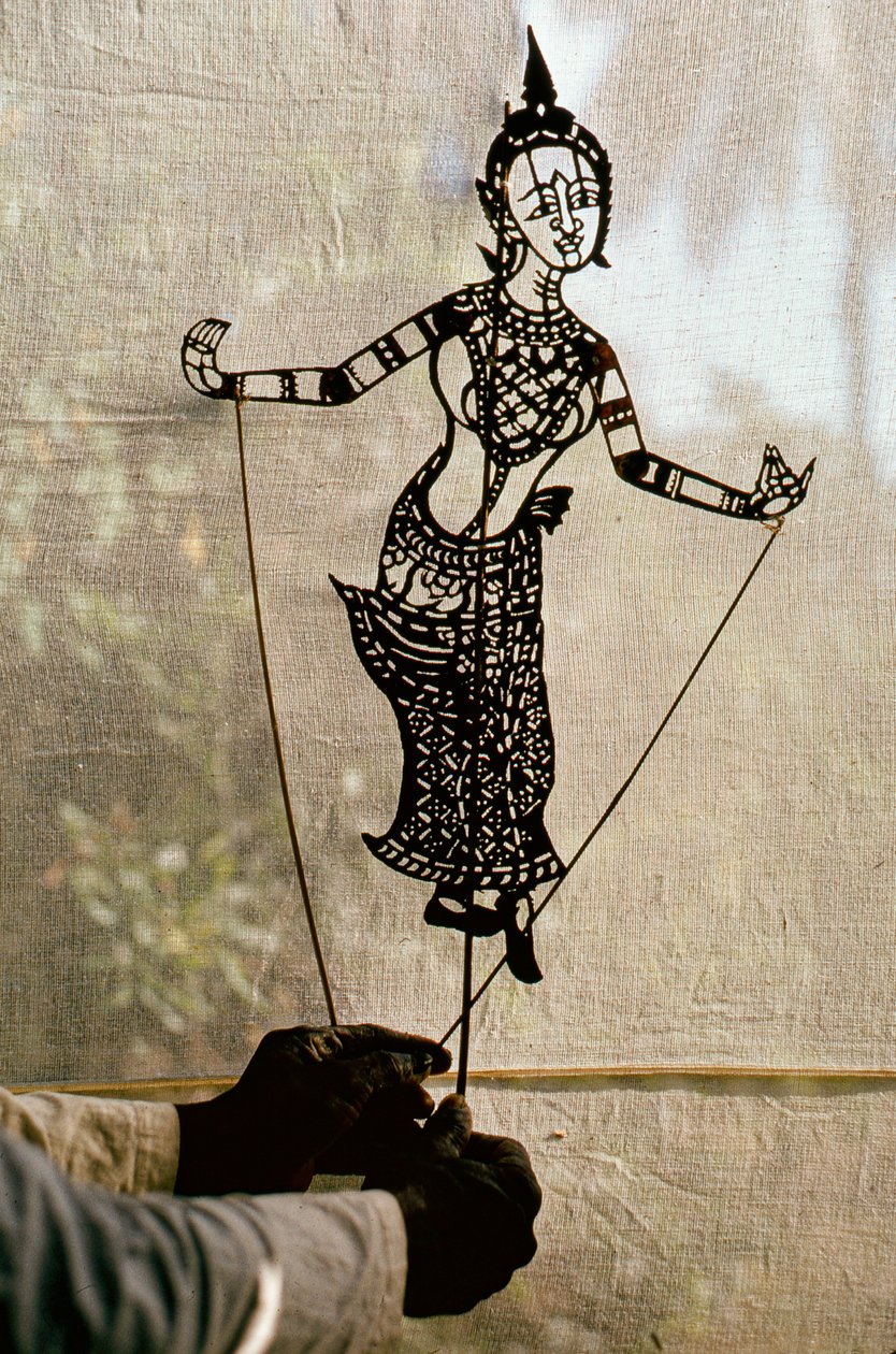 O marionetista manipula uma marioneta de sombras para contar histórias contra uma tela para um jogo de sombras. C... de Thomas J. Abercrombie