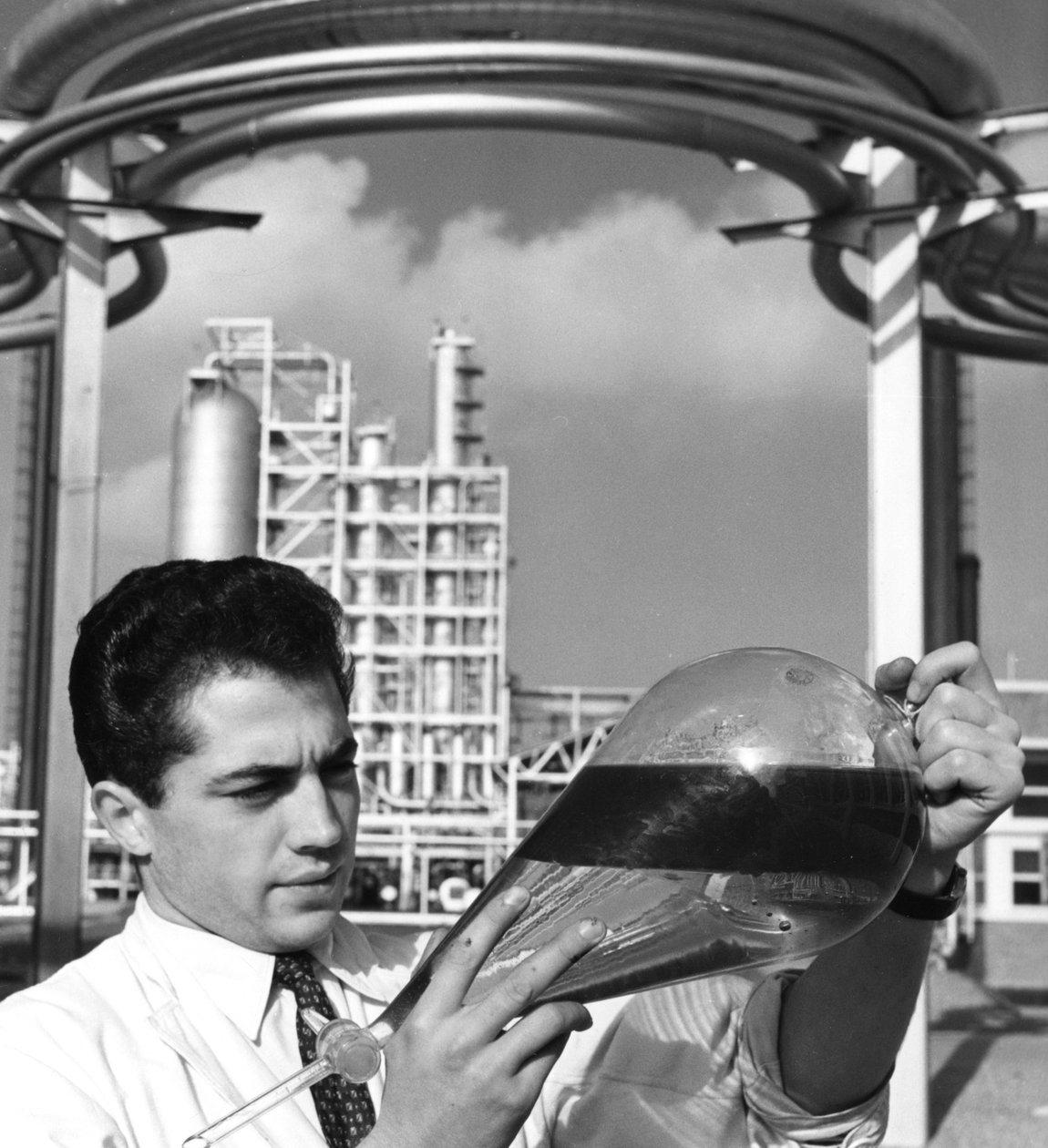 Um trabalhador de laboratório detém um funil de separação de petróleo, refinaria de Dunquerque, França, década de 1950 de Unbekannt