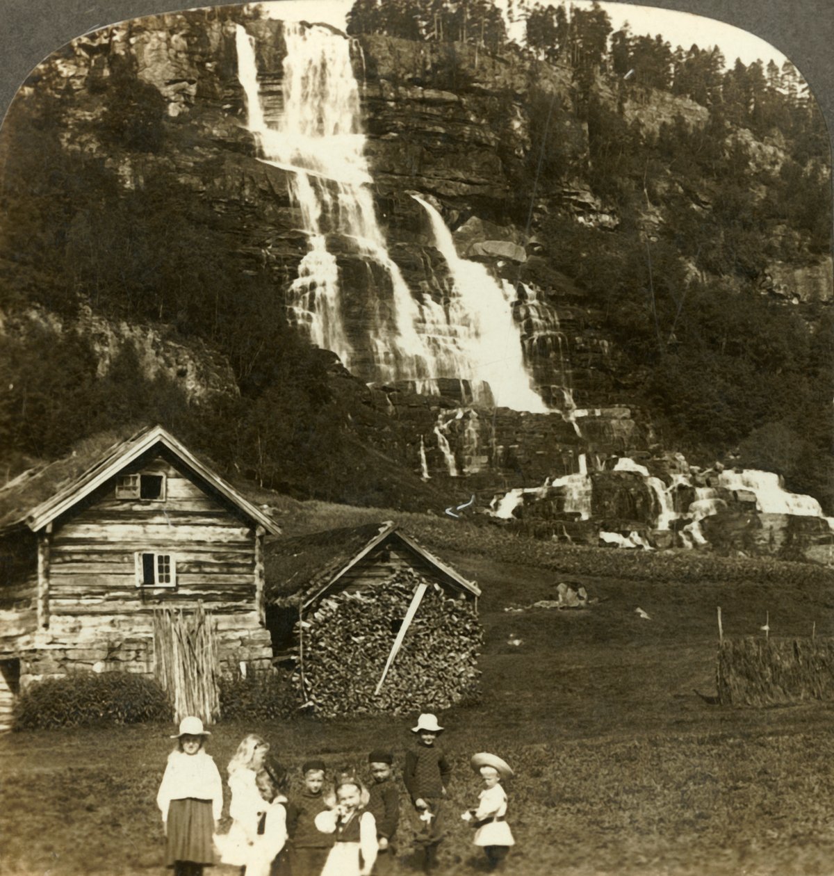 As crianças brincam em um campo de agricultores com cascata em terraços de Tvinde, Vossevangen, Noruega, c1905. de Unbekannt