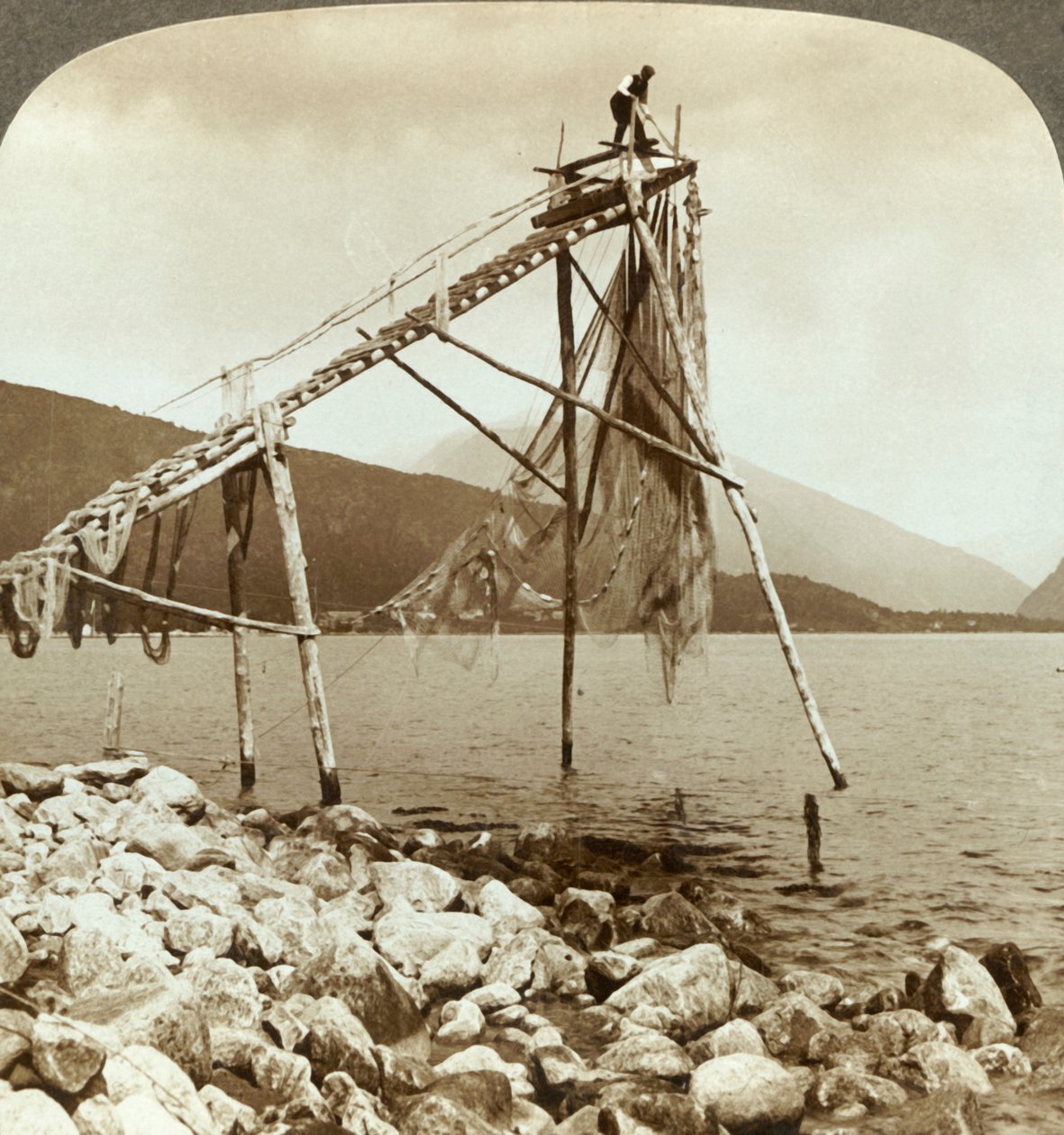 Pescador que arranja redes salmon em Balestrand em Sognefjord - Balholm na distância, Noruega, c1905. de Unbekannt
