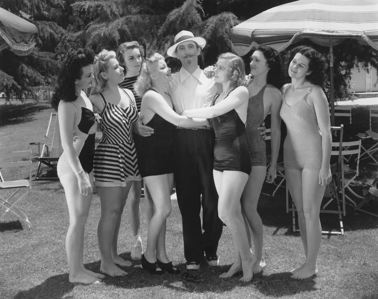 Hollywood, Califórnia: c.1935 Sete jovens mulheres em fato de banho disputam a atenção de um único homem. (foto a p/b) de Unbekannt