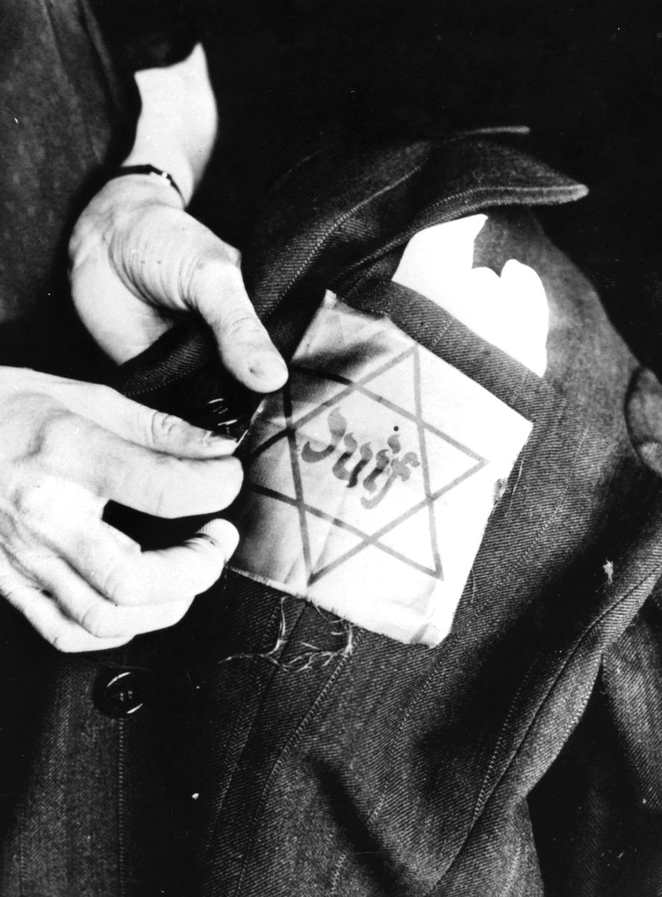 Costurando a estrela amarela identificando um judeu em uma jaqueta, Paris ocupada pela Alemanha, 1942 de Unbekannt