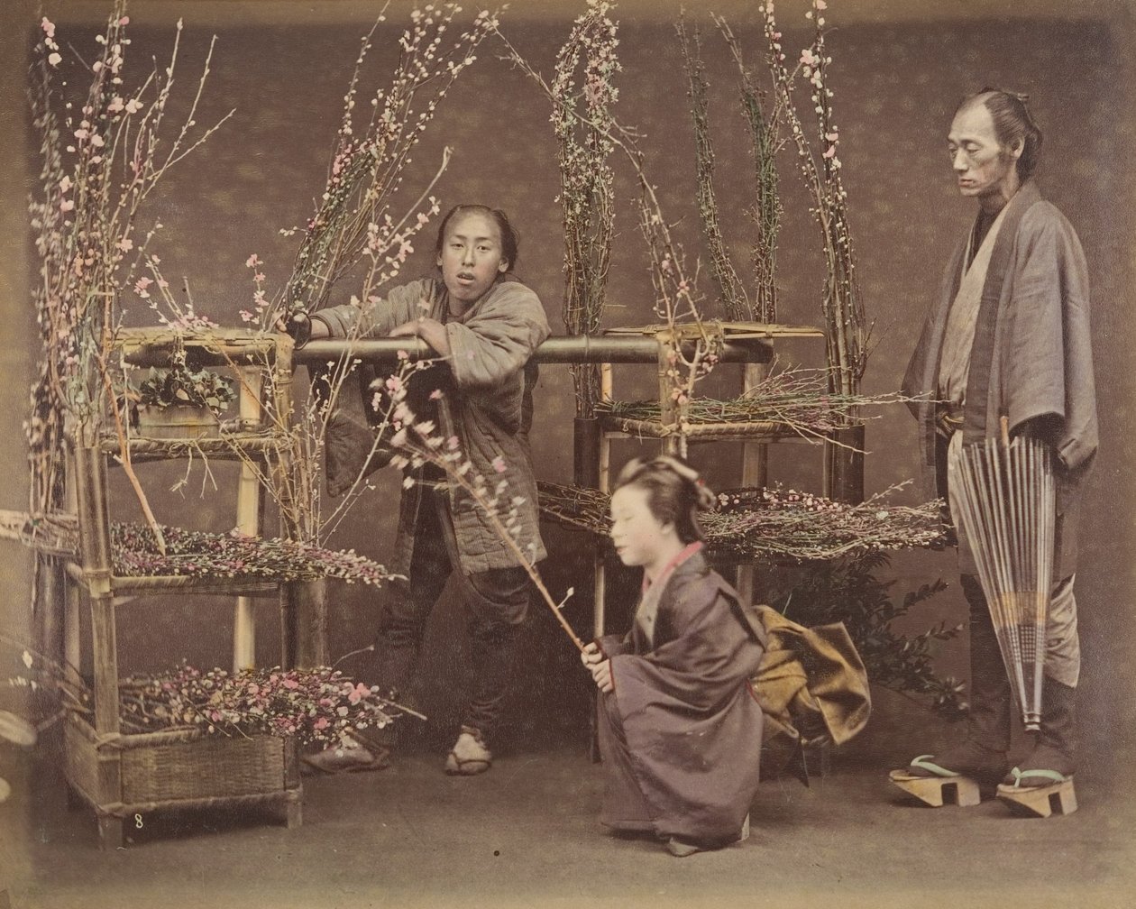 [Dois homens japoneses e uma mulher japonesa posando com galhos floridos], década de 1870., de Unbekannt