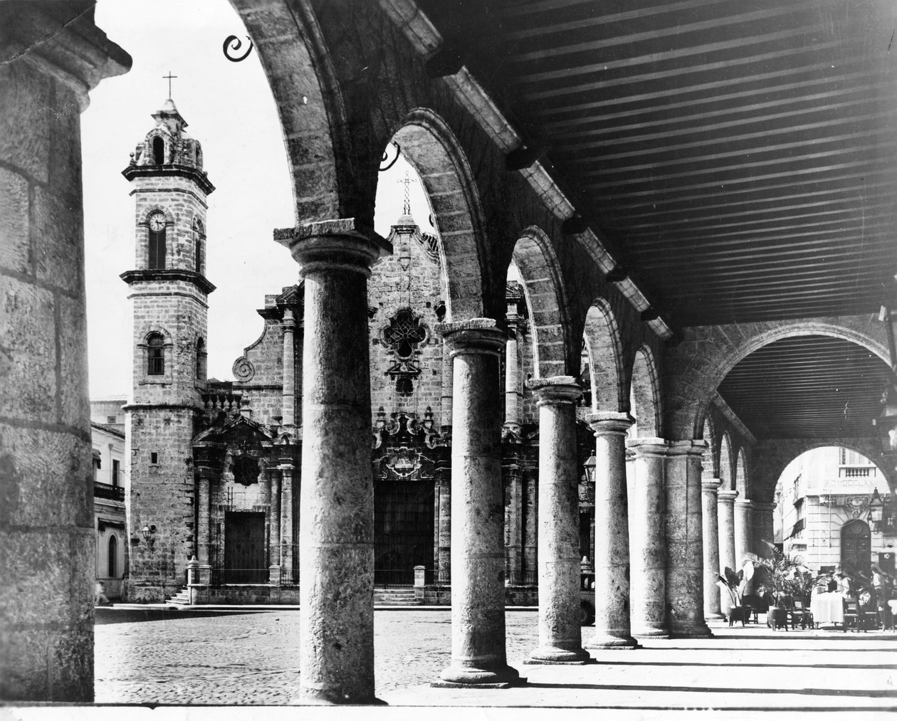 Uma vista da Praça da Antiga Catedral de Havana é emoldurada pelos magníficos arcos de um prédio adjacente, 1954 de Unbekannt Unbekannt