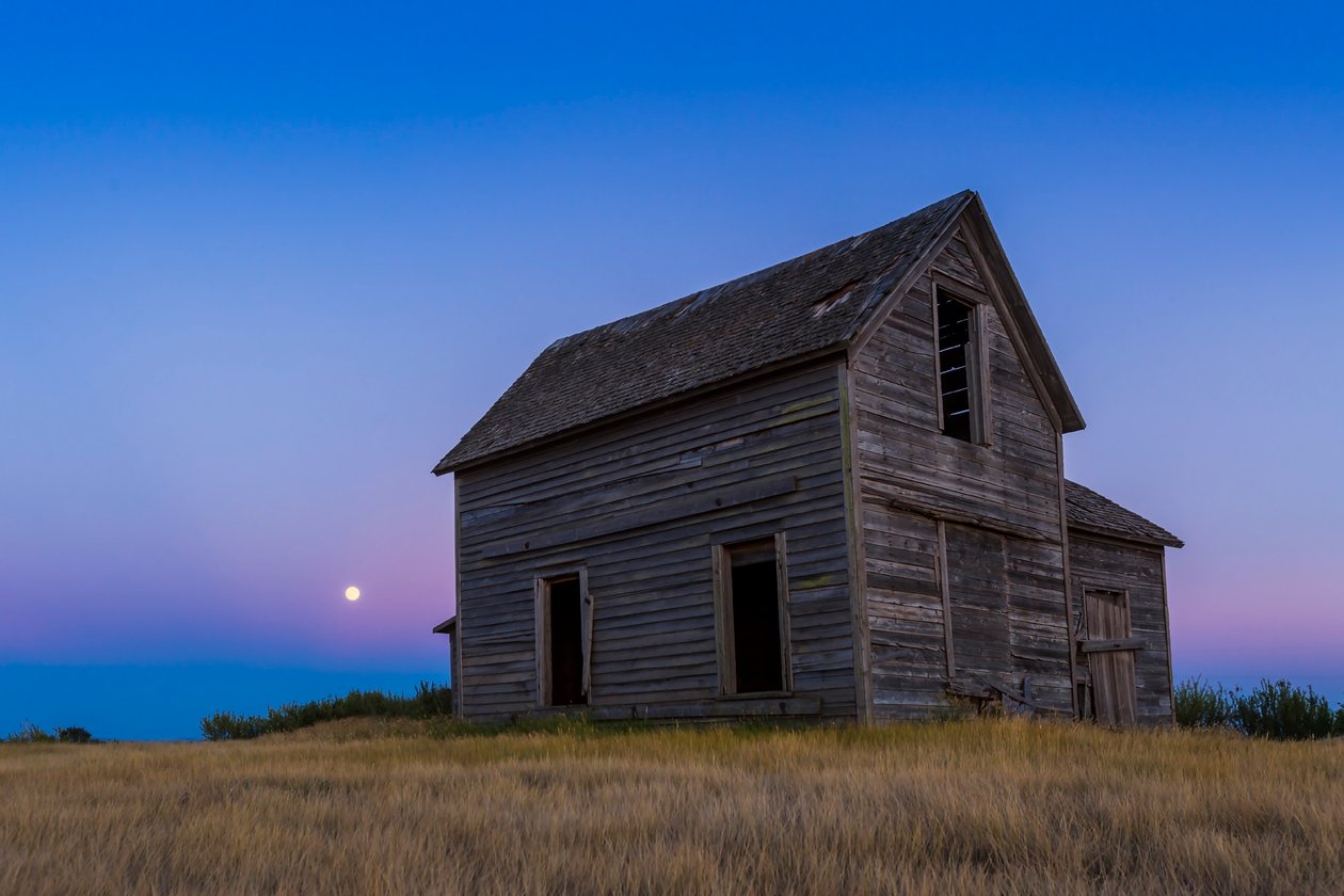 A lua quase cheia, uma lua azul de 30 de julho de 2015, levantando-se atrás de uma antiga fazenda rústica perto de Bow Island, Alberta de Unbekannt Unbekannt