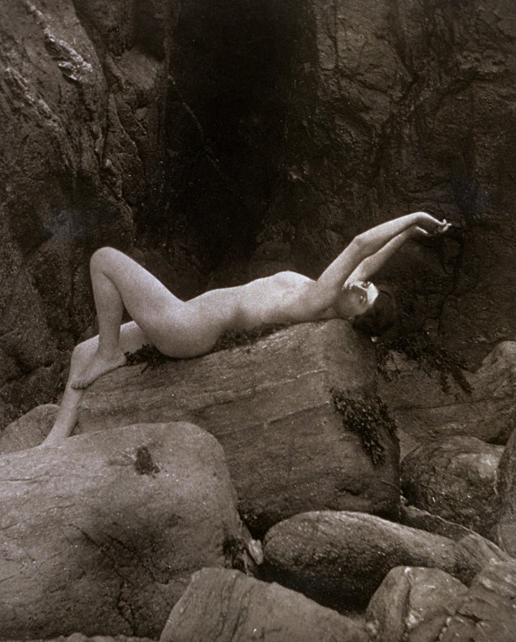 Uma jovem mulher nua numa pose artística reclinada numa rocha de Unbekannter Künstler