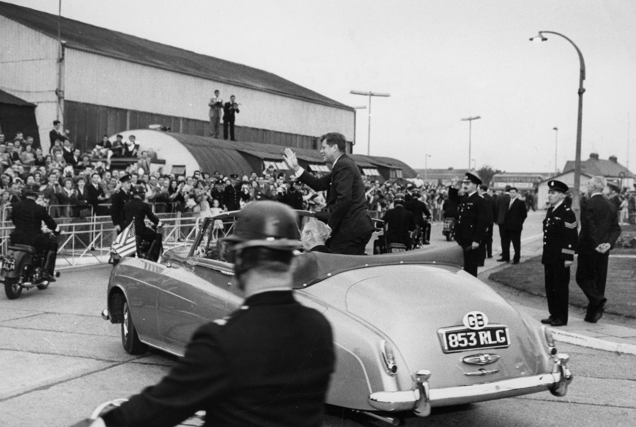 Depois de inspecionar uma Guarda de Honra Naval no Aeroporto de Londres, o Presidente Kennedy e o Sr. Macmillan saem de carro, em um carro aberto. de Unbekannt