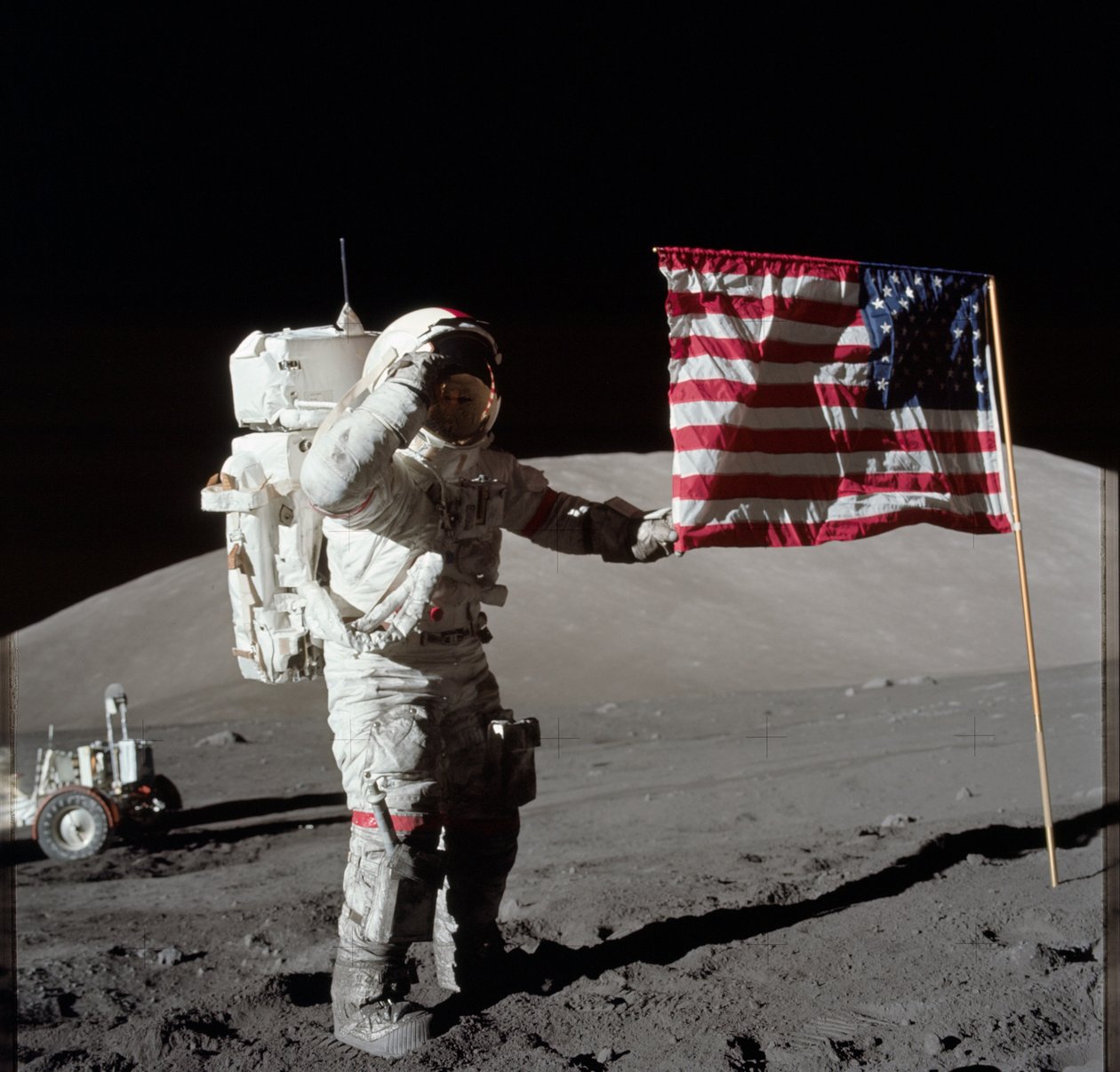 O astronauta Eugene A. Cernan, comandante da Apollo 17, é fotografado ao lado da bandeira dos Estados Unidos durante a atividade extraveicular de superfície lunar (EVA) no local de desembarque do Taurus-Littrow. A parte mais alta da bandeira parece apontar de Unbekannt