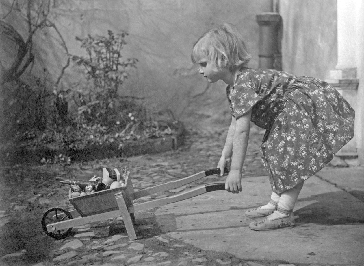 Uma menina a brincar com um carrinho de mão. Fotografia por volta de 1931 de Unbekannt