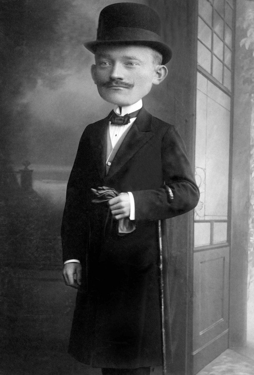 Retrato de um homem muito elegante com uma cabeça de gigante, usa um chapéu de melão, uma bengala, um laço e um casaco preto. Trata-se de uma fotomontagem. Annees 1910 Fotografia histórica, homem com cabeça de gigante de Unbekannter Künstler