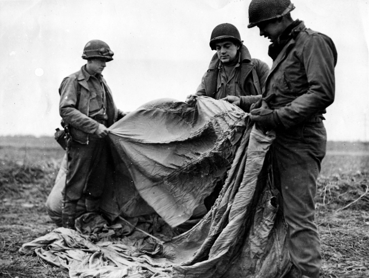 Segunda Guerra Mundial (1939-1945) - Segunda Guerra Mundial (II Guerra Mundial ou 2ª Guerra Mundial): Perto de Kornelmunster (Alemanha), 17 de Dezembro de 1944: Infantaria do 1º Exército dos EUA examinam um pára-quedas alemão usado na noite anterior ao dia de Unbekannt
