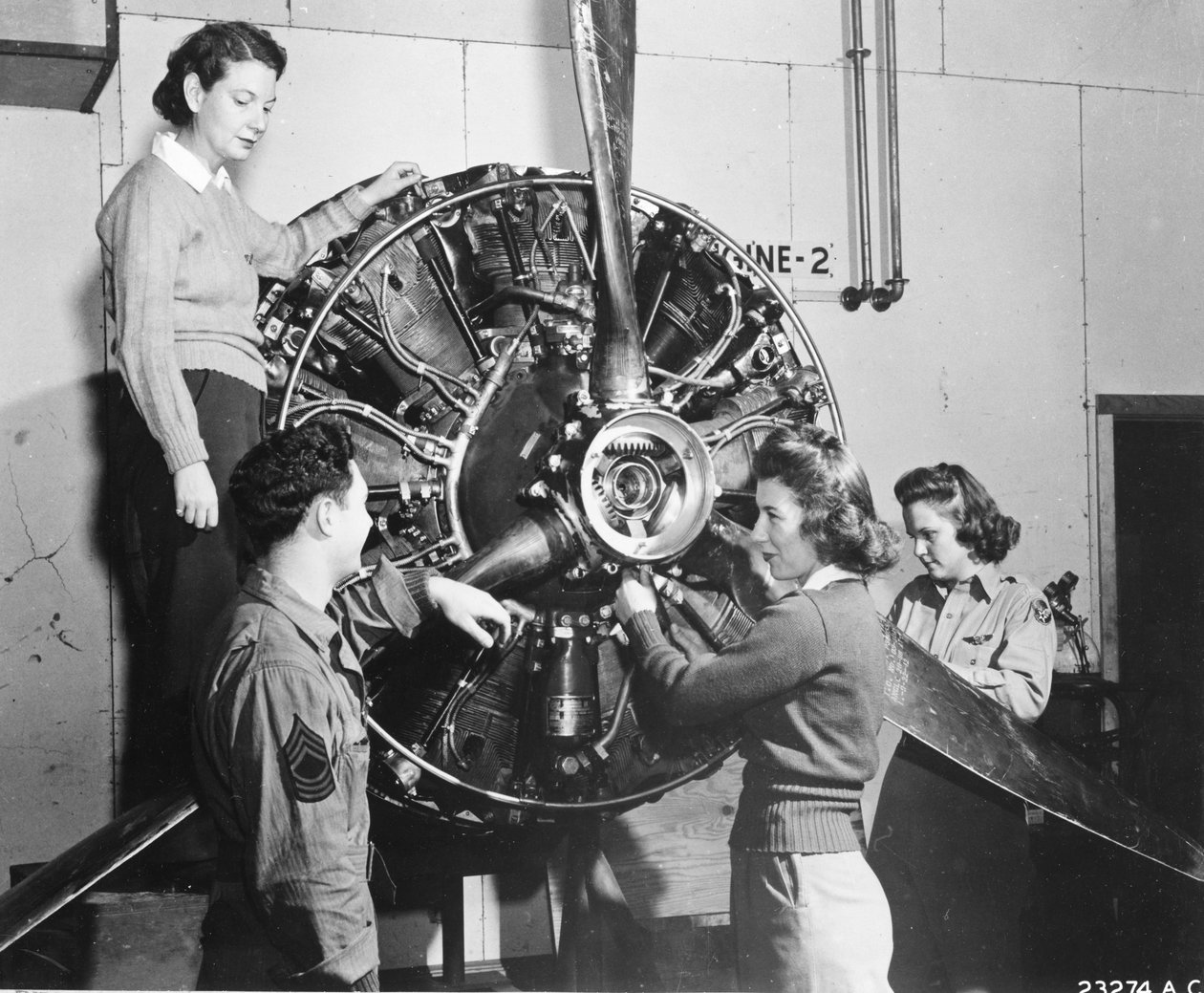 Vespas aprendem de onde vem a energia no motor B-17 Flying Fortress enquanto assistem ao treinamento de pilotos B-17 no Lockbourne AAB, trabalhando no mecanismo da hélice, enquanto um chefe de tripulação observa, eles são (l-r): Patricia Bowser, Ann Waldne de Benjamin Baud