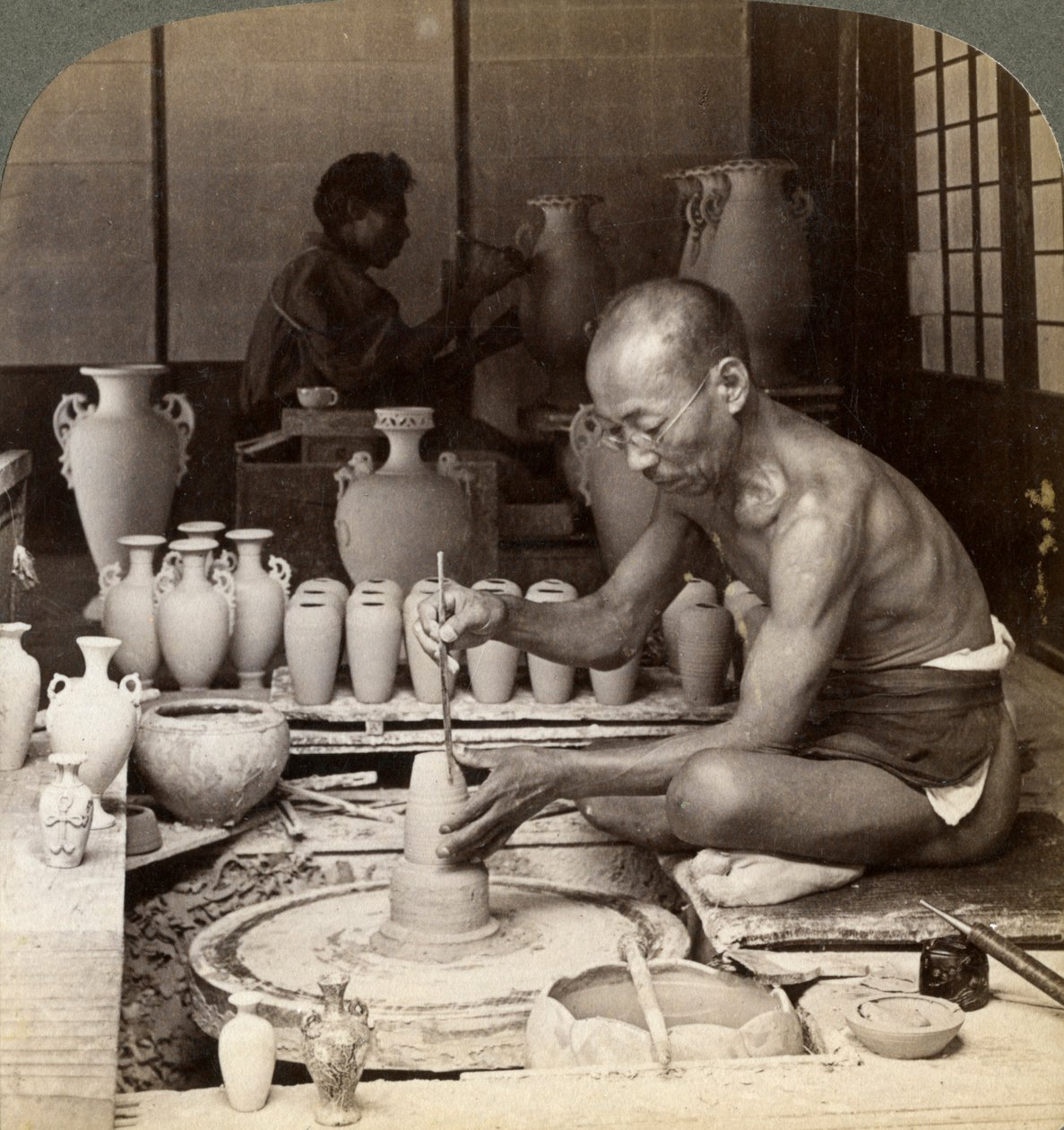 Um oleiro e sua roda, formando um vaso de porcelana Awata, Kinkosan trabalha, Kyoto, Japão, 1904 de Underwood and Underwood