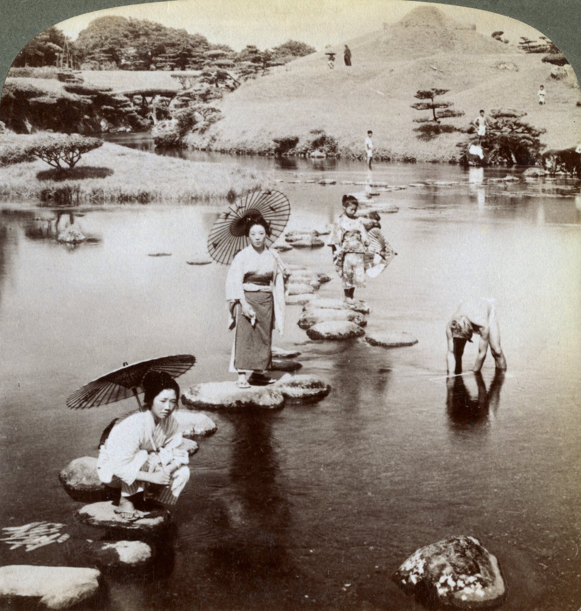 Mulheres que cruzam o lago em alpondras, jardim de Suizen-ji, Kumamoto, Japão, 1904. de Underwood and Underwood