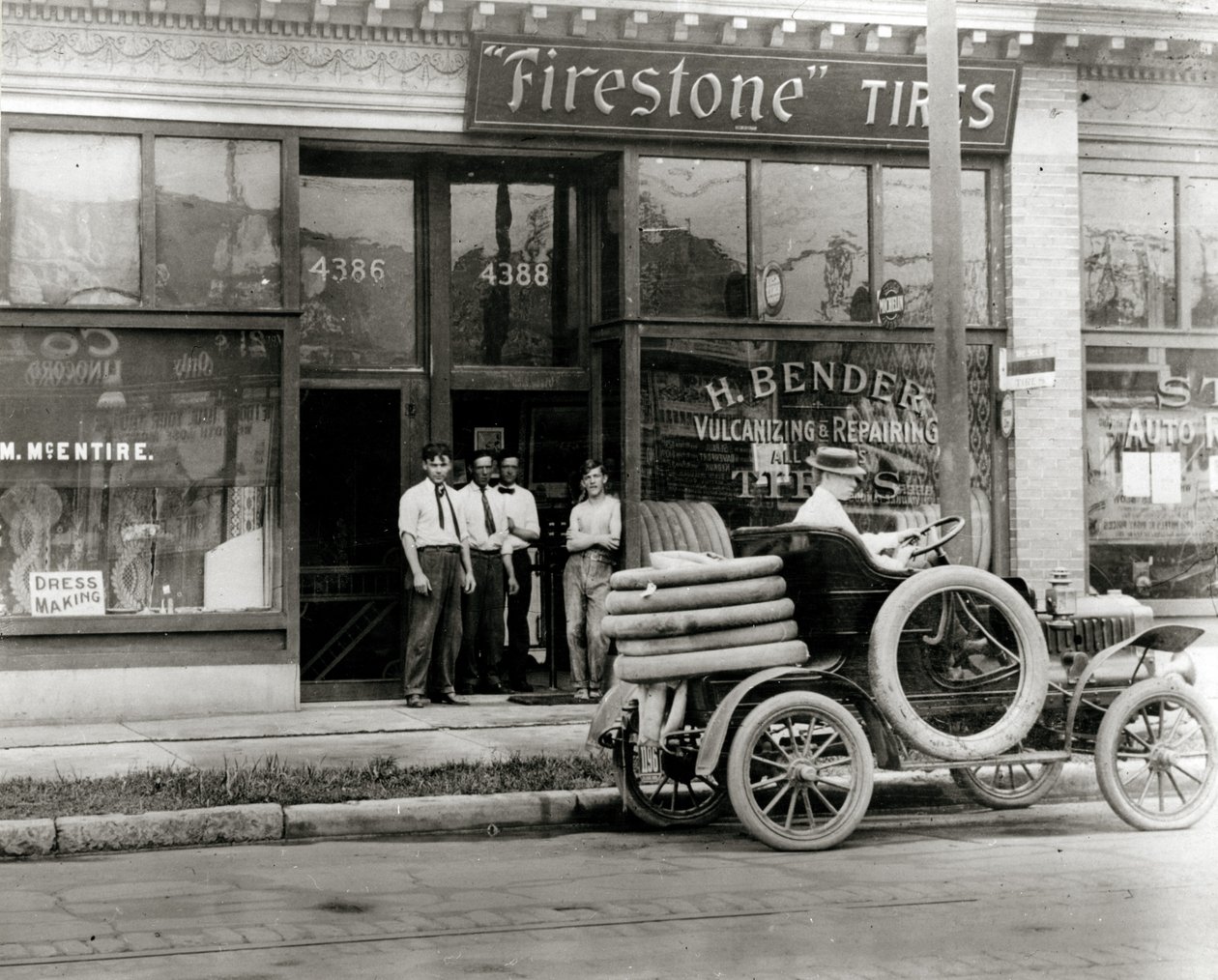 Homens e caminhão de reparação de pneus de automóvel se reuniram do lado de fora da concessionária H. Bender Firestone Tire em 4388 Olive Street de Unknown