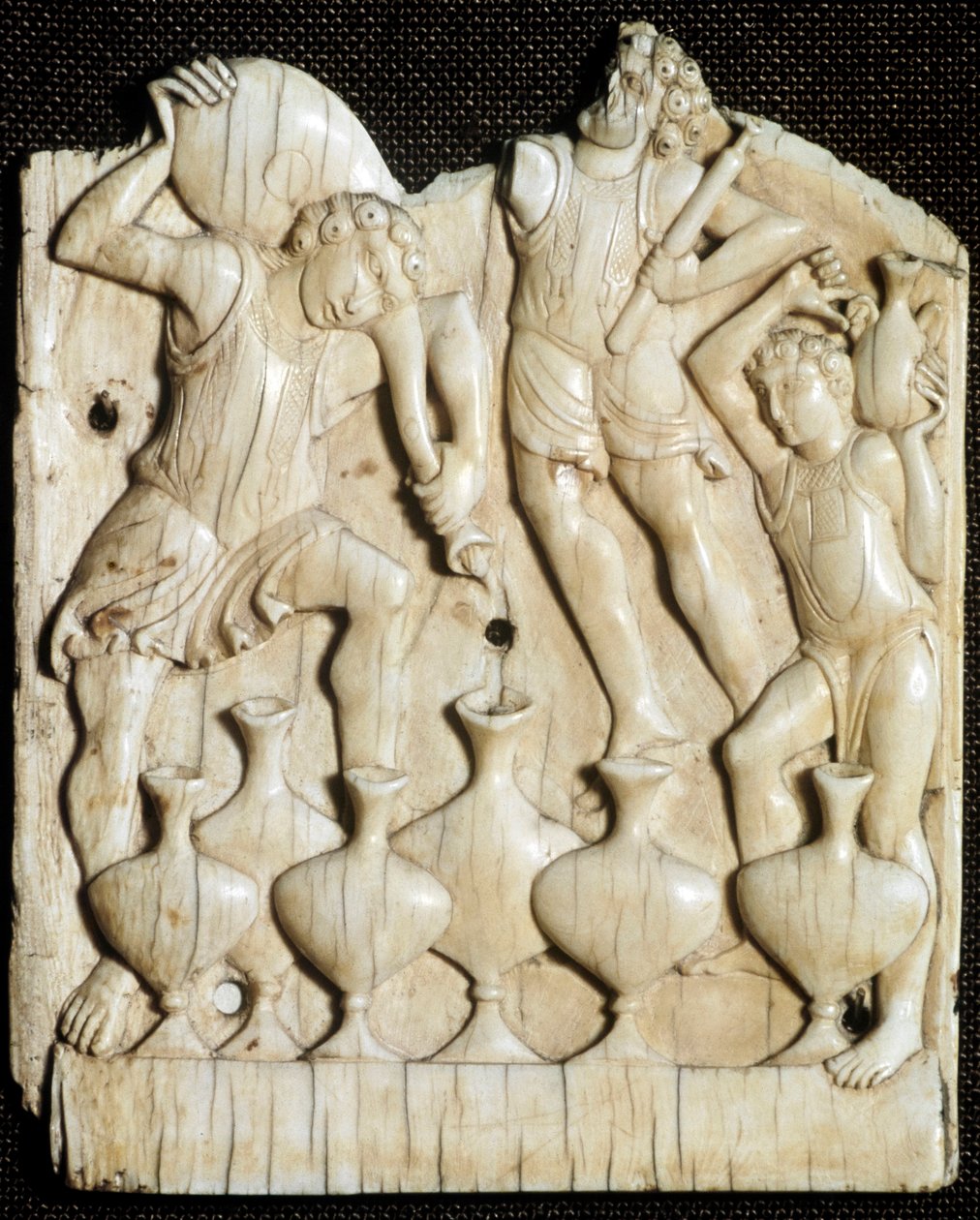 Casamento de Caná: "os servos enchem de água seis potes que Jesus Cristo transformará em vinho" Tábua de marfim esculpida. Londres do século XI, Victoria e Albert Museum de Unknown artist