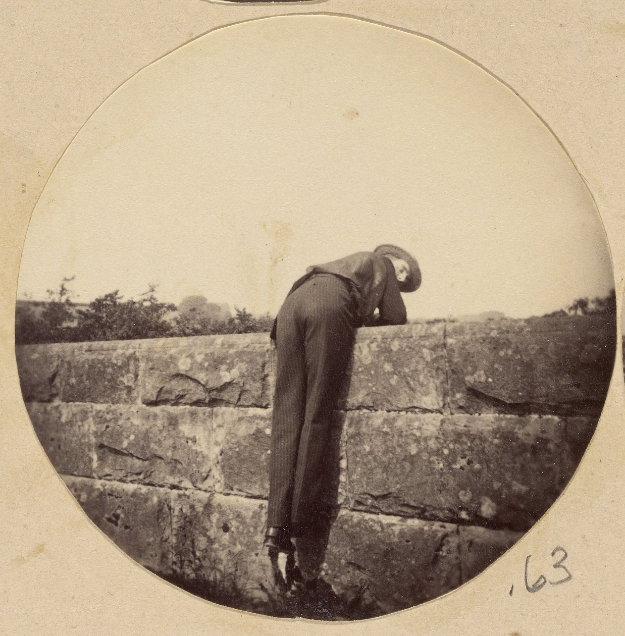 [Homem de chapéu debruçado sobre um muro de pedra]. de Unknown artist