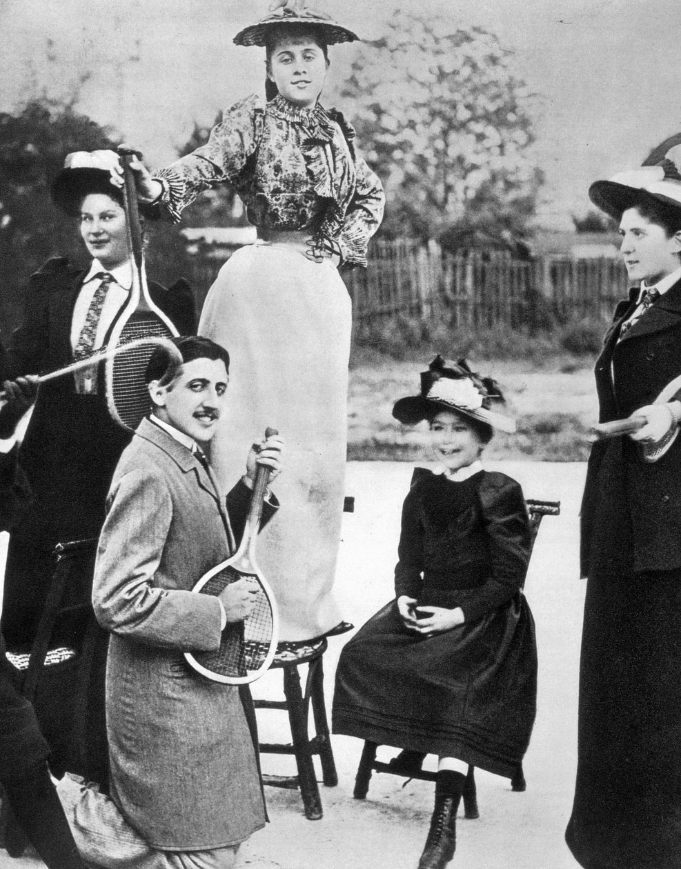 Marcel Proust, no meio de um grupo de jovens mulheres, tocando guitarra numa raquete de ténis no Bineau Boulevard em Paris de Unknown photographer