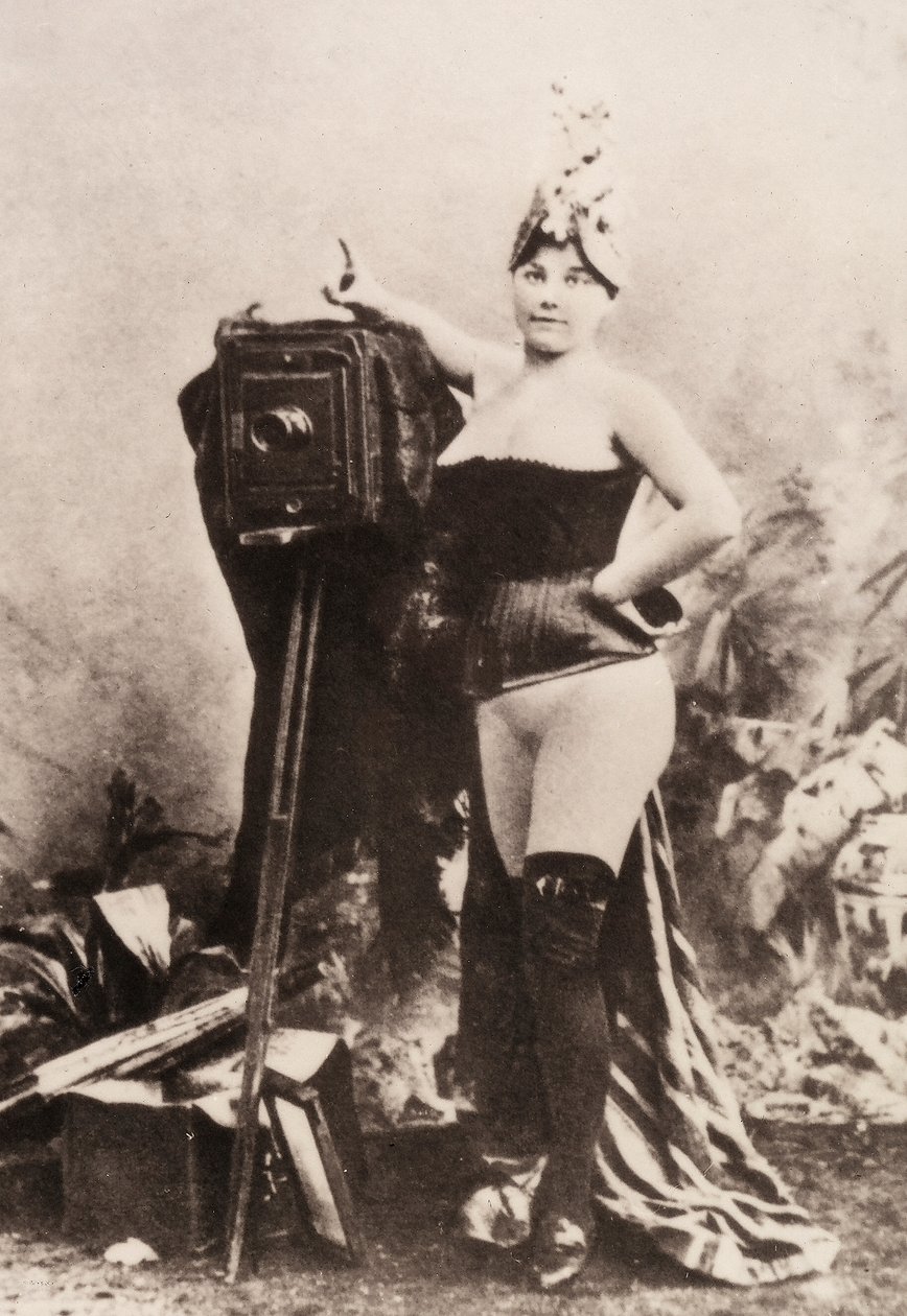 Retrato de uma mulher parcialmente nua, apoiada numa máquina fotográfica antiga. de Unknown photographer