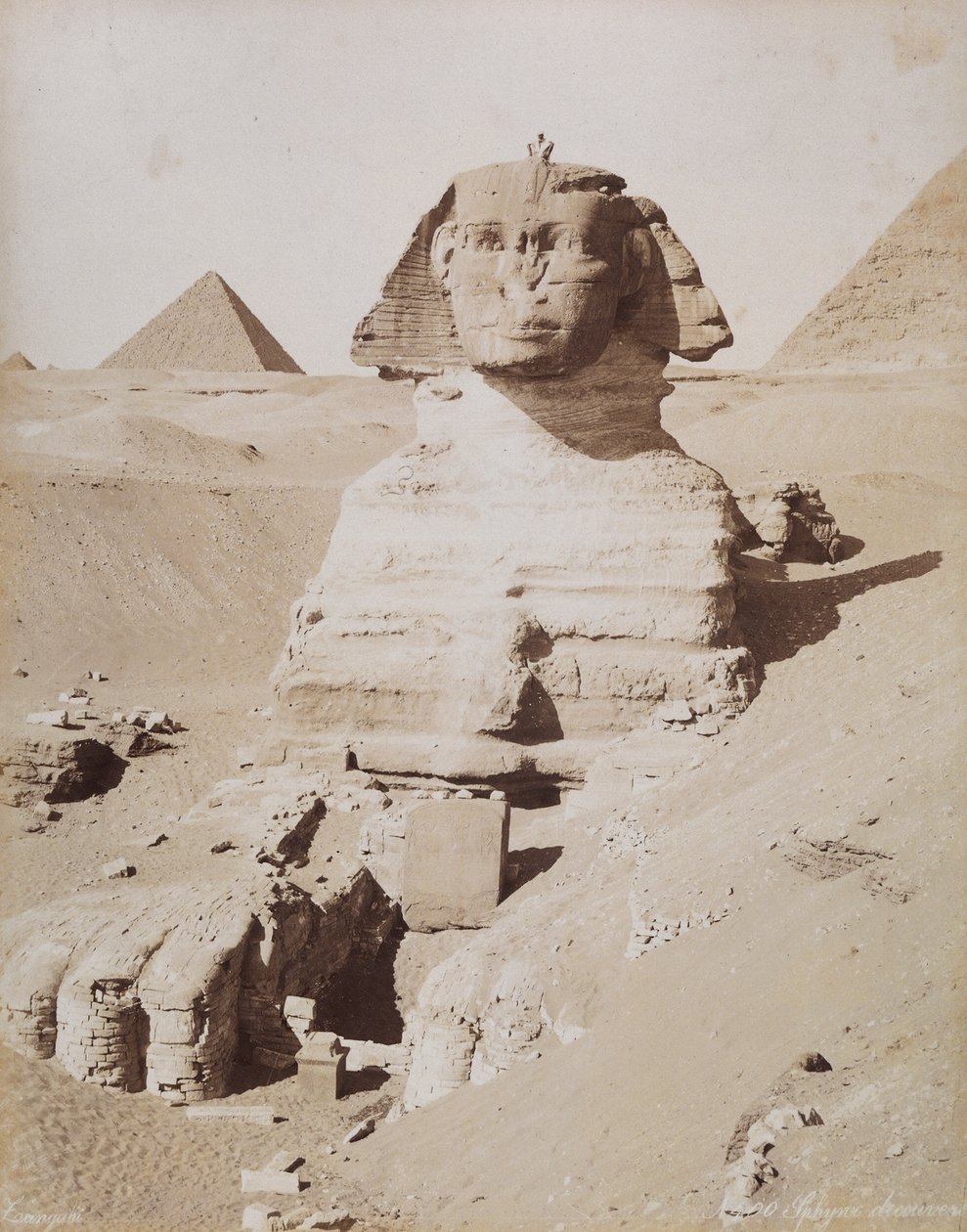 A Esfinge e, ao fundo, a Grande Pirâmide de Quéops. Cairo, El Giza de Unknown photographer