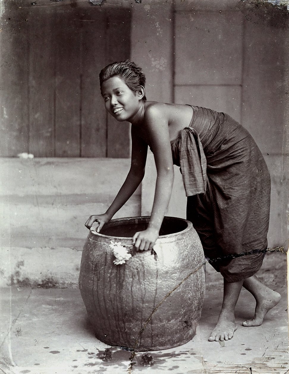 Jovem tailandesa sorridente, a empurrar um contentor grande de Unknown photographer