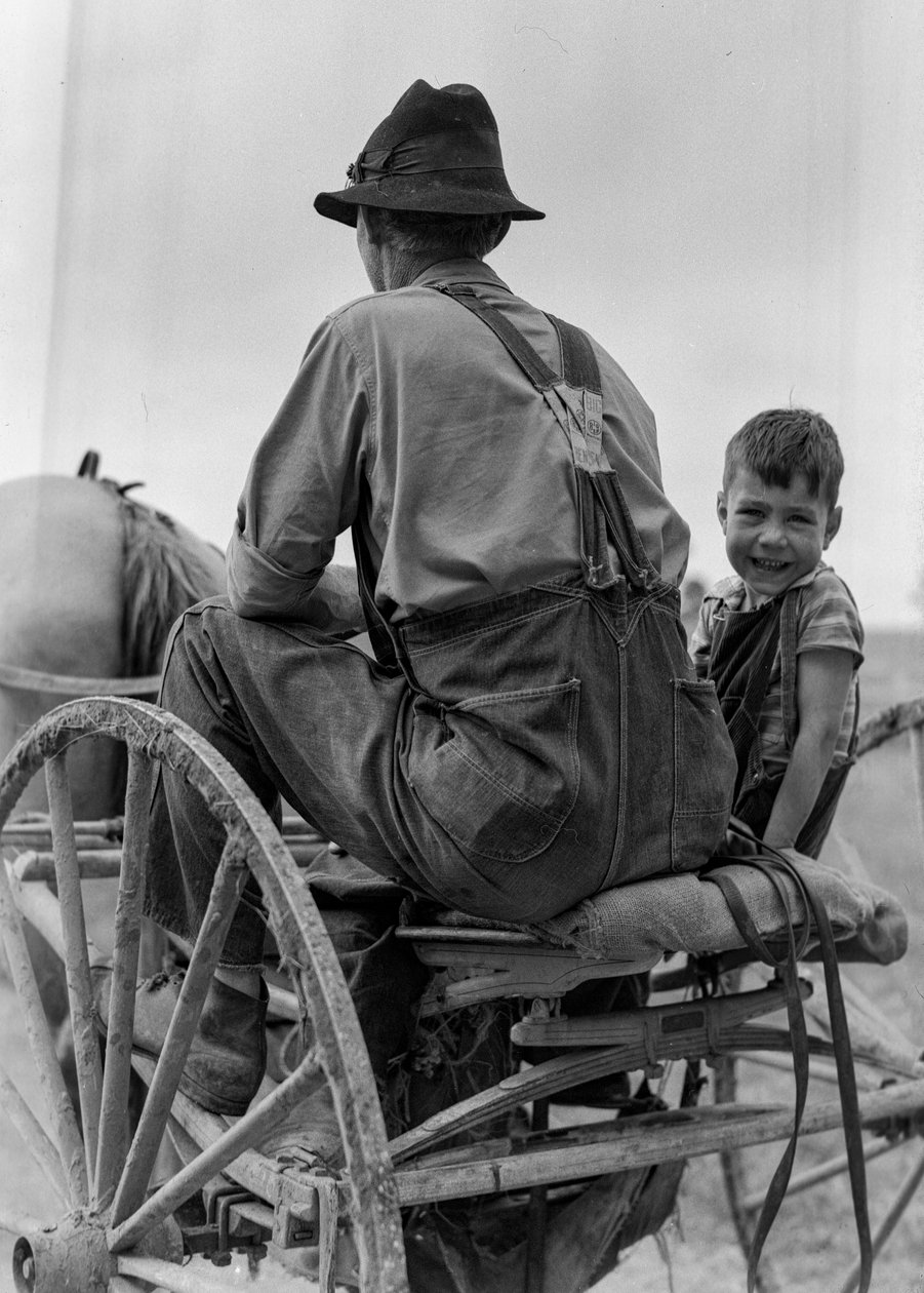 Agricultor e rapaz sorridente andam no assento de uma charrete puxada por cavalos na Virgínia Ocidental de Volkmar Wentzel