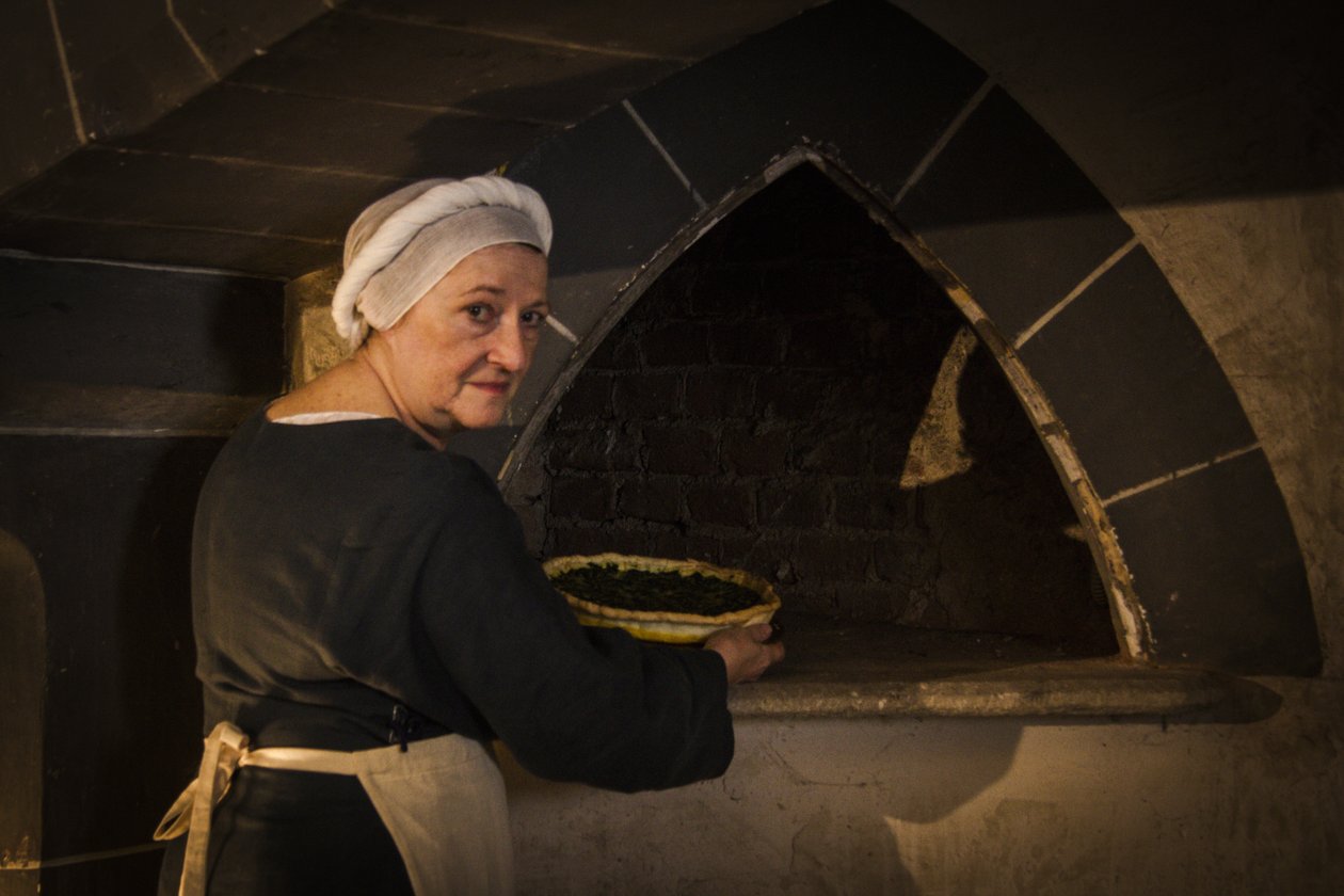 Reencenação histórica: Criada colocando bolo no forno da cozinha do castelo de John Ward Dunsmore