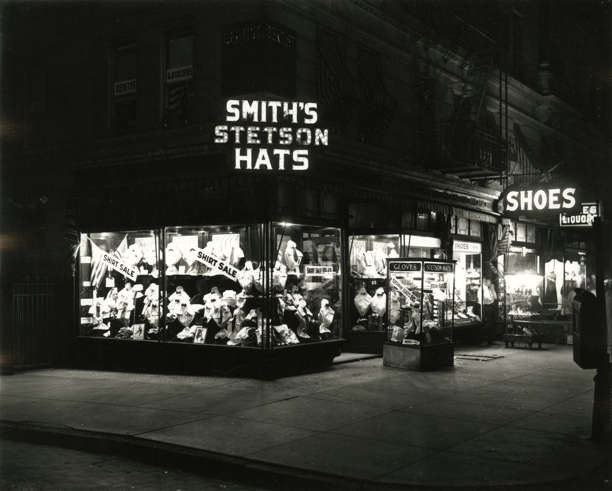 Frentes de loja iluminadas anunciando chapéus de Stetson de Smith, sapatos, licores, c.1910-21 de William Davis Hassler
