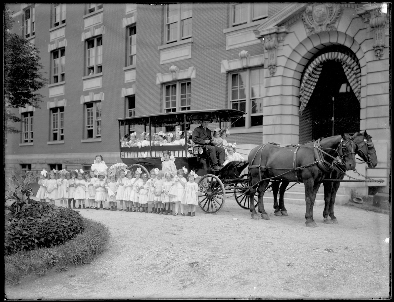 As meninas pequenas colocam dentro e na frente de um vagão puxado por cavalos, na frente de um edifício não identificado, provavelmente o asilo órfão católico romano, Kingsbridge, Bronx, c.1910 de William Davis Hassler