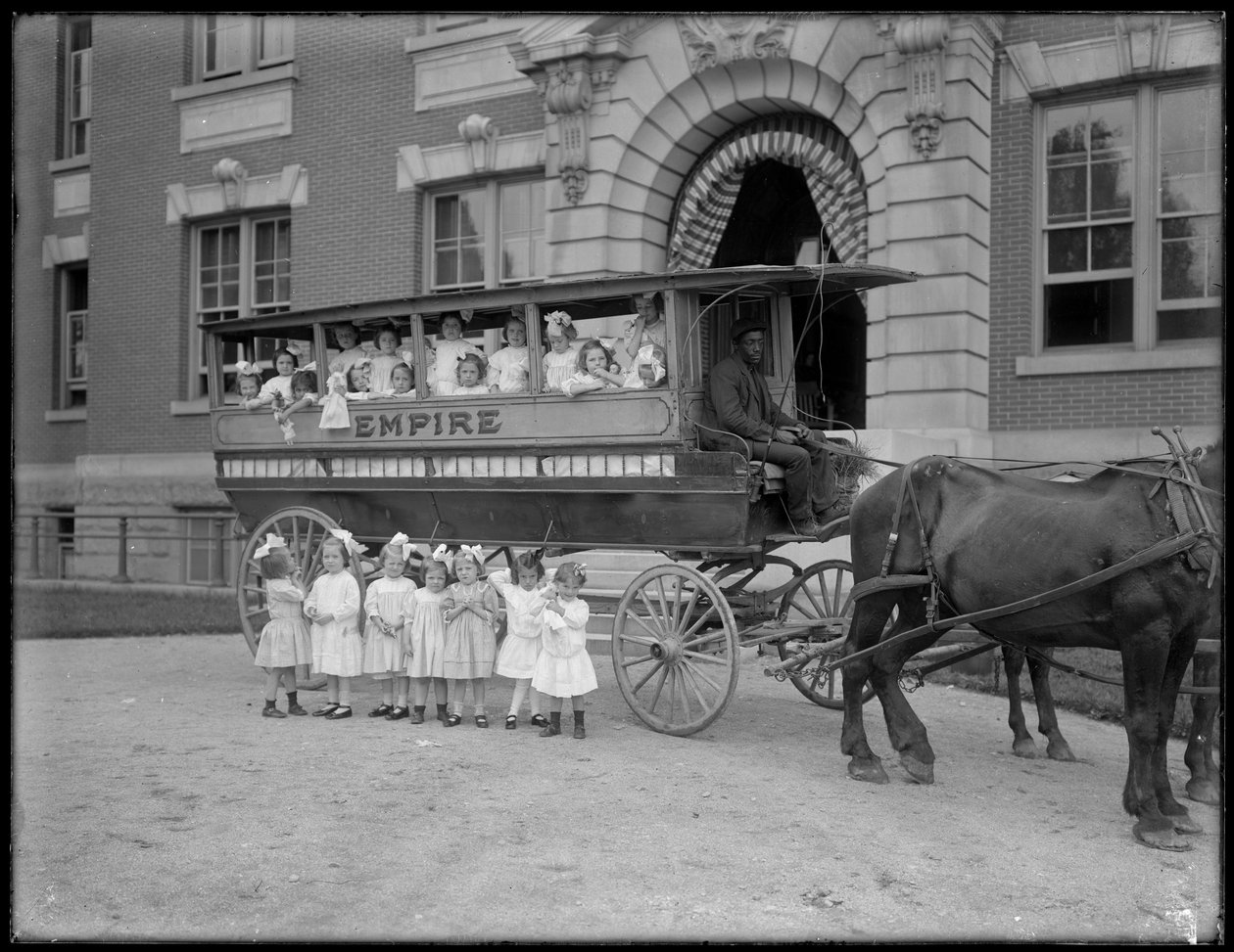 As meninas pequenas colocam dentro e na frente de um vagão puxado por cavalos, na frente de um edifício não identificado, provavelmente o asilo órfão católico romano, Kingsbridge, Bronx, c.1910 de William Davis Hassler